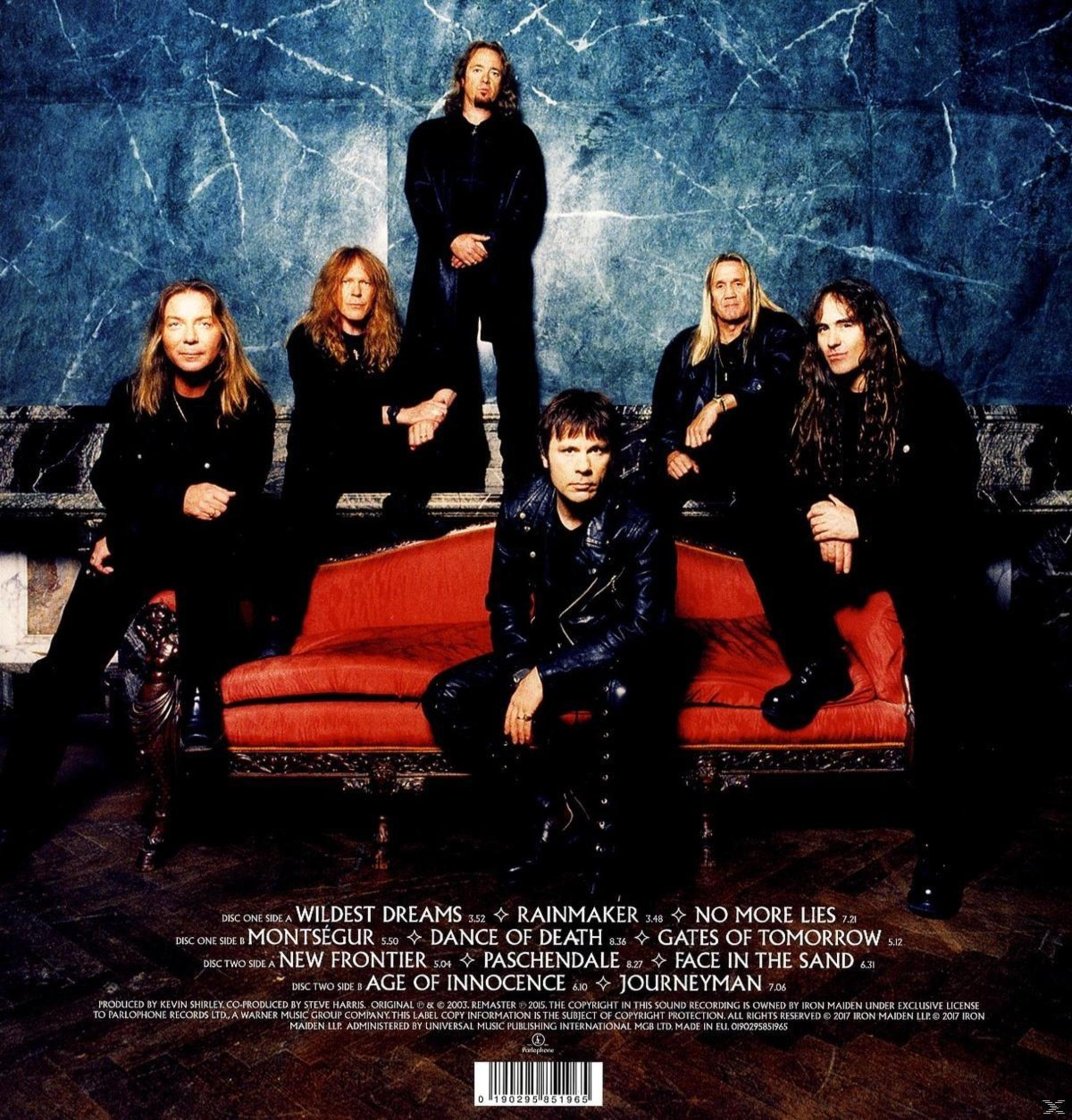 Foto della band Iron Maiden. Sei uomini in nero, seduti e in piedi su un divano rosso.