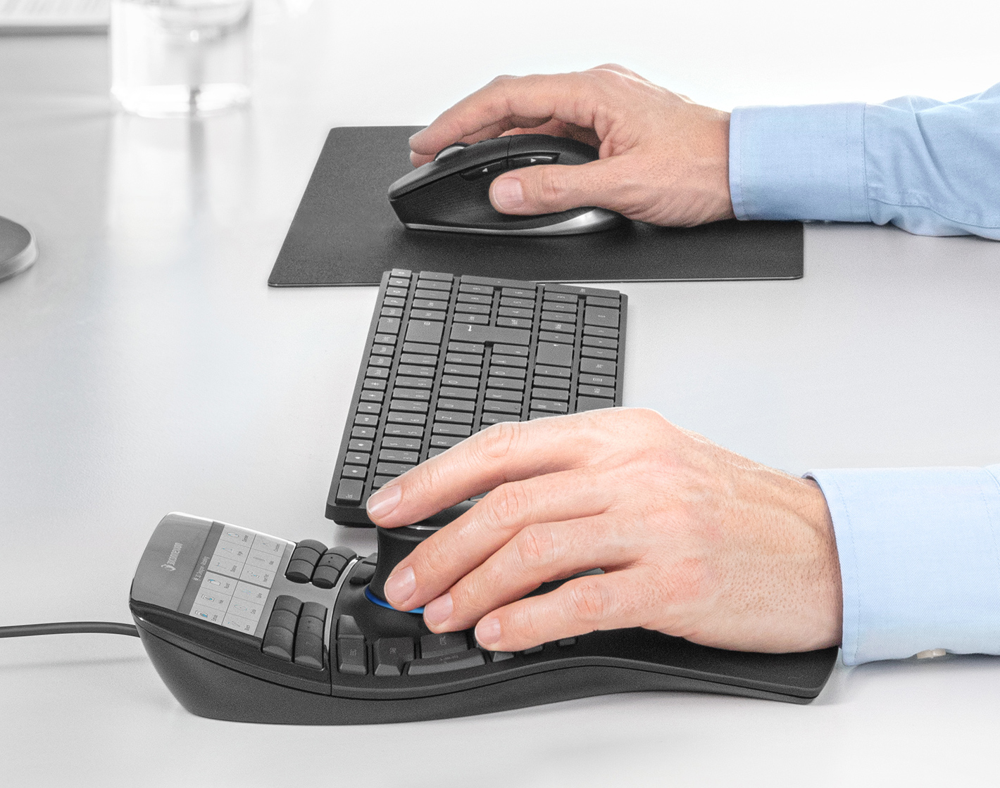 Hands using a keyboard and mouse. The keyboard is split, and the mouse is ergonomic.
