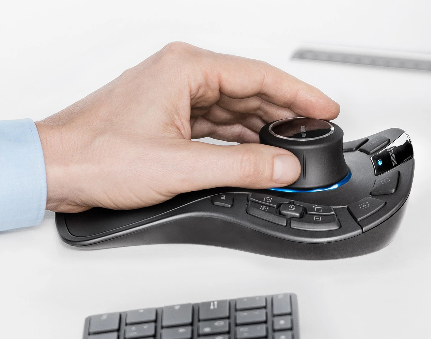 A person's hand holding a black 3D mouse on a white surface.