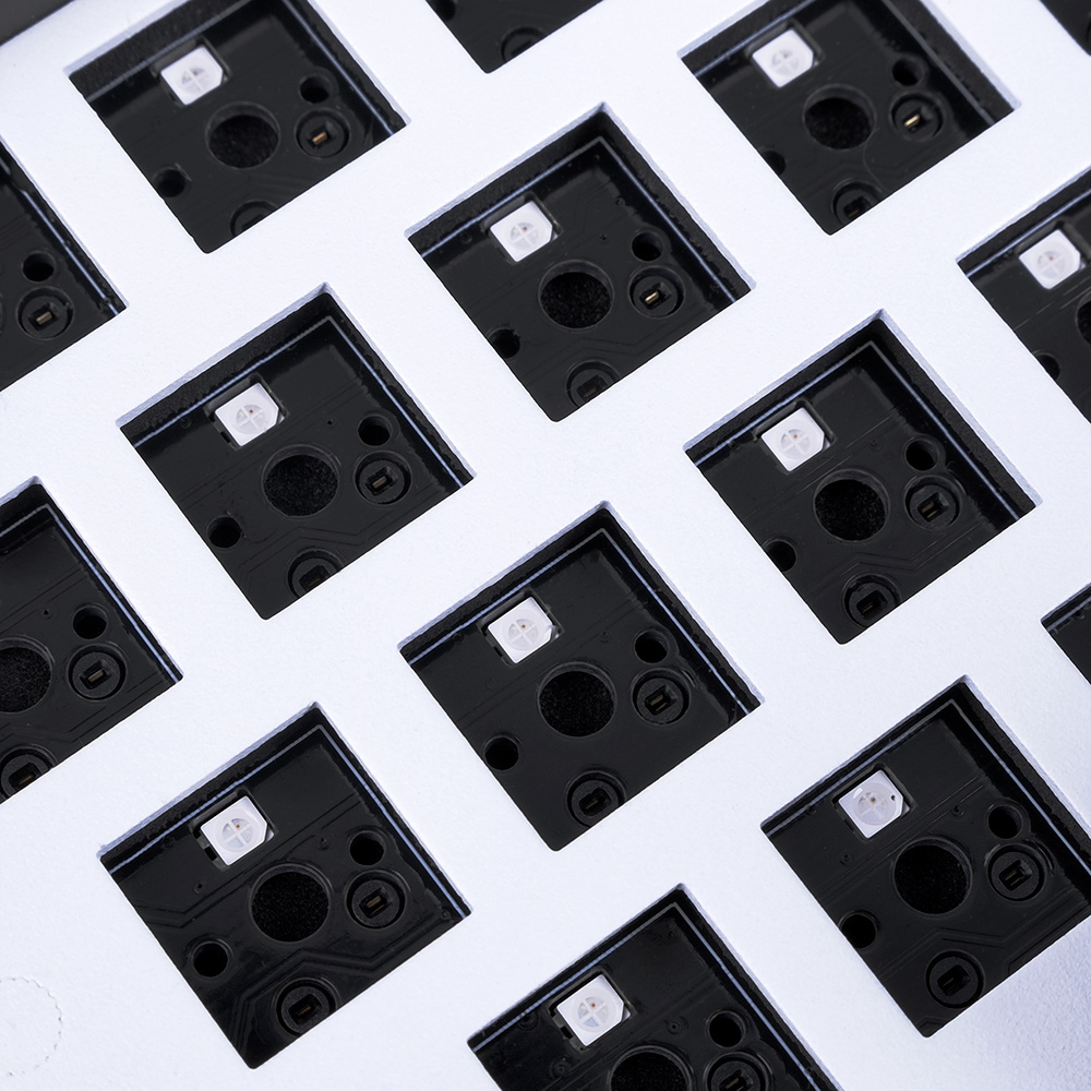 Nahaufnahme einer weißen Tastaturbasis mit schwarzen Quadraten. Weiße LEDs befinden sich in den Quadraten.