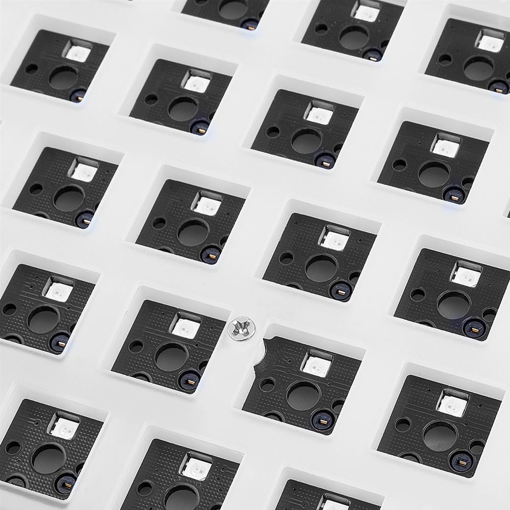 Zbliżenie białej podstawy klawiatury z czarnymi kwadratami. Wewnątrz każdego kwadratu znajduje się białe złącze.