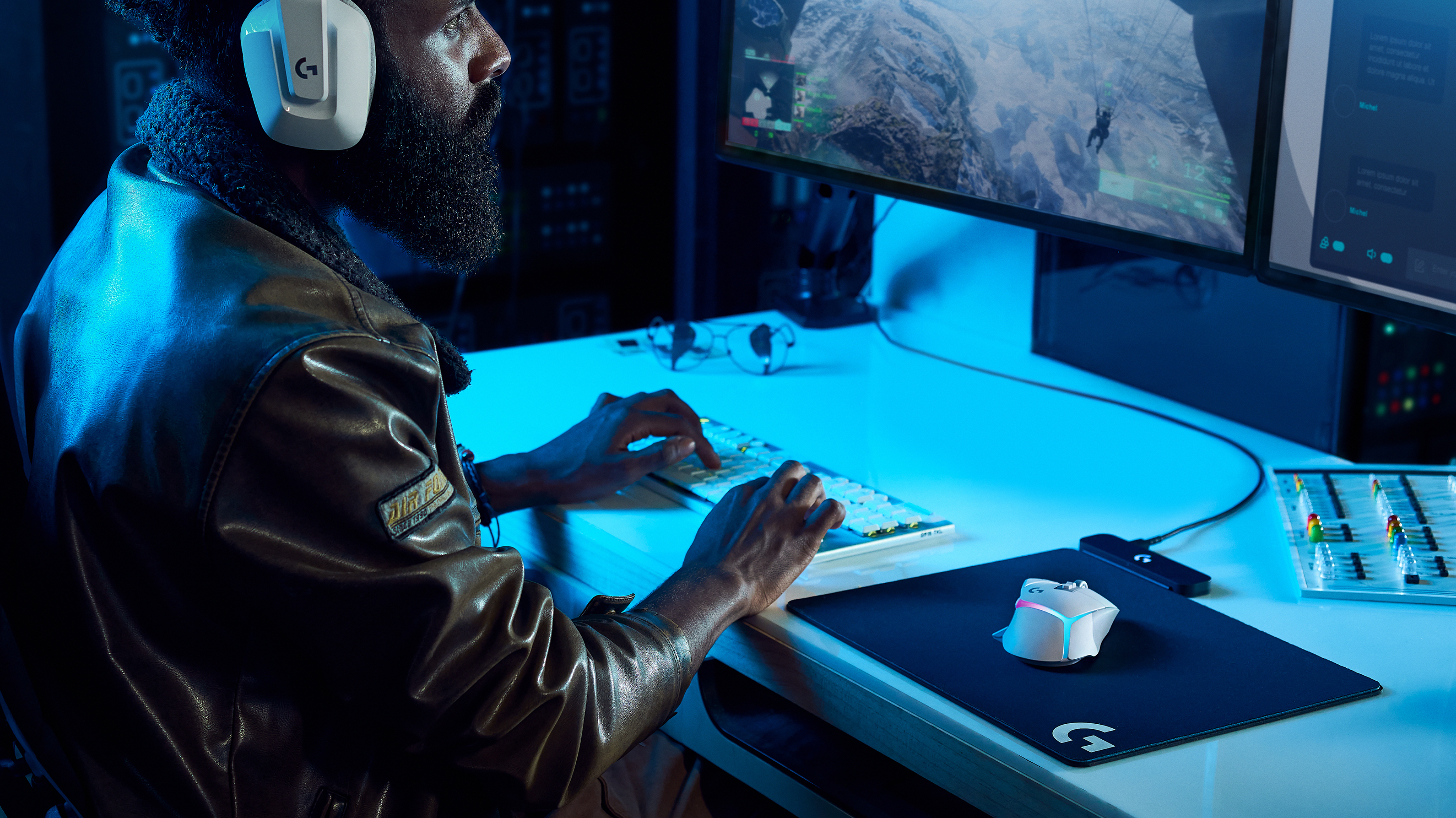 Gracz w pokoju z dwoma monitorami, słuchawkami, klawiaturą i myszą.