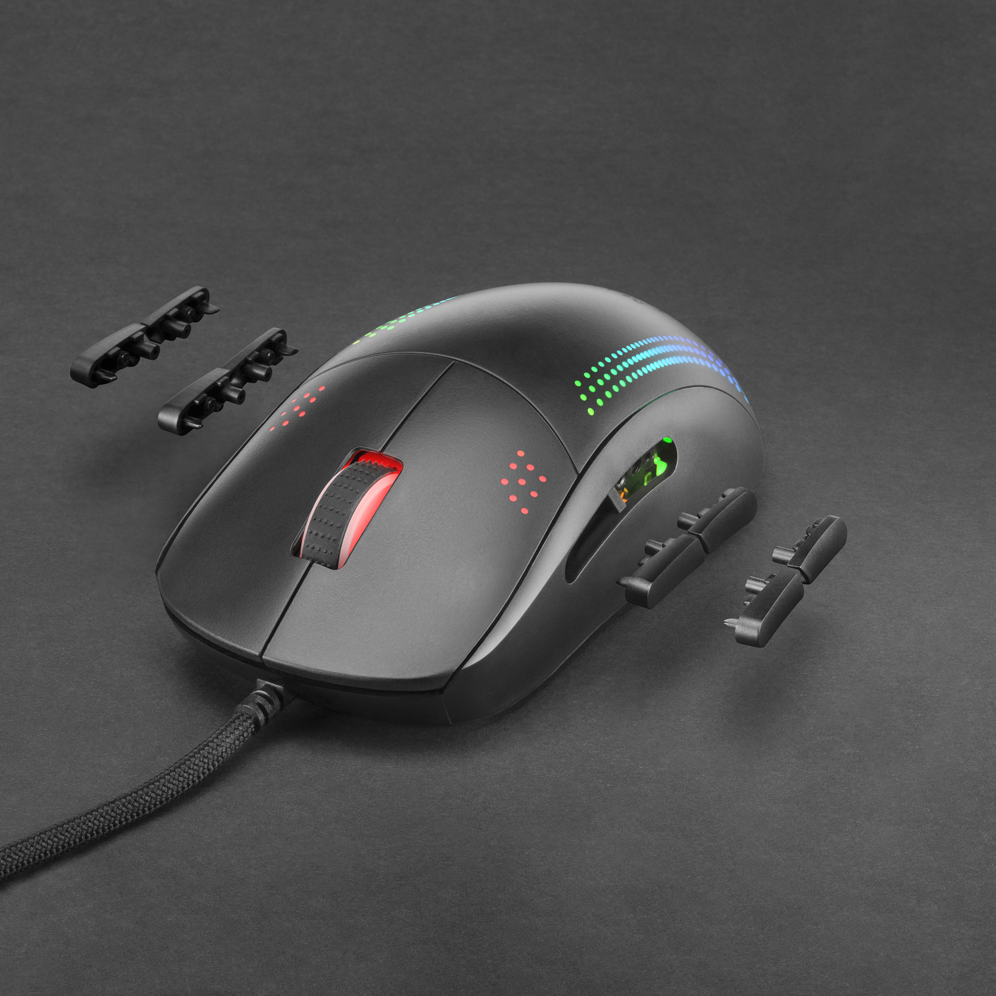 Un ratón para juegos negro con luces de colores y botones laterales extraíbles. El ratón está sobre una superficie oscura.