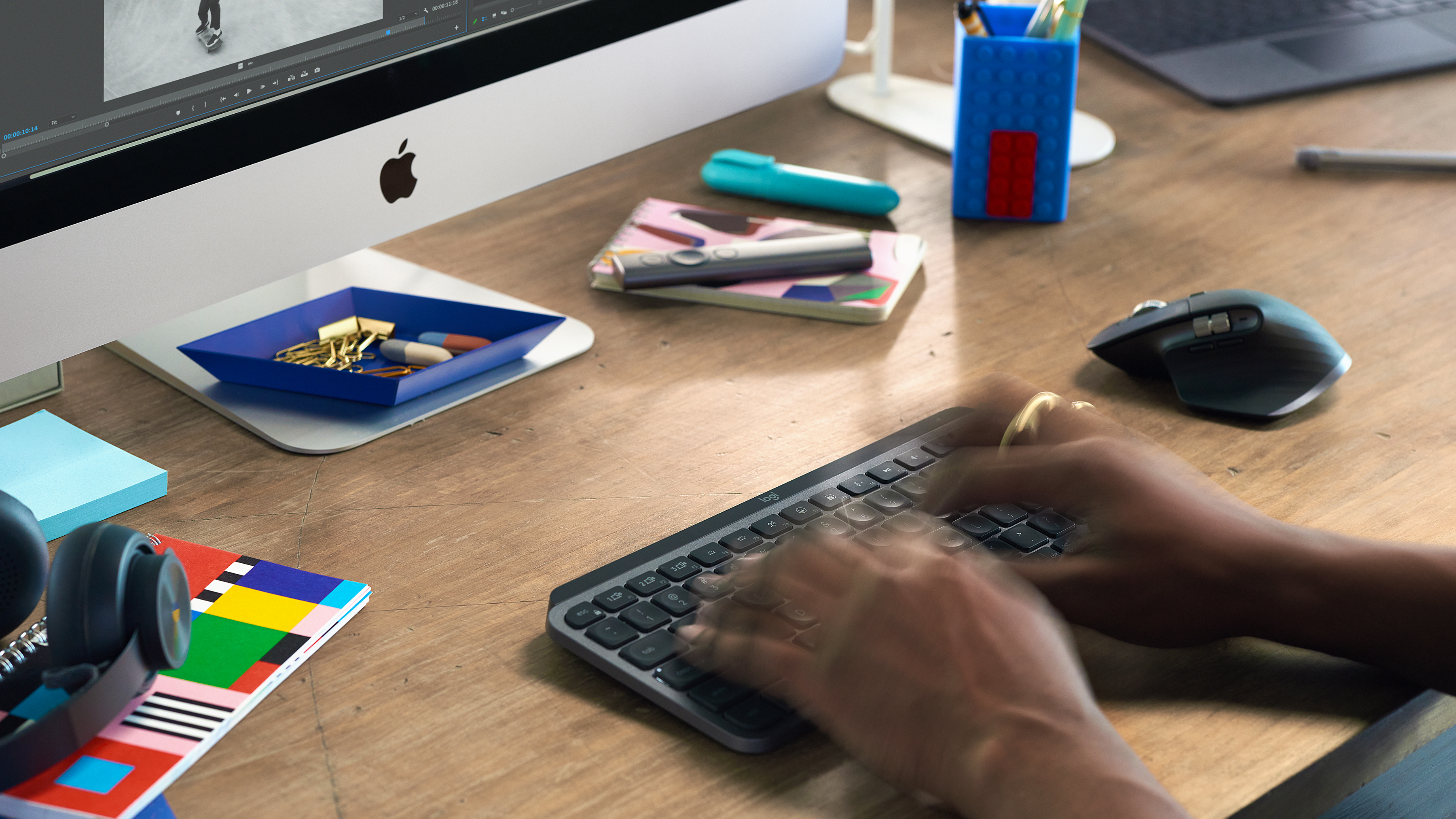 Dłonie piszące na klawiaturze. Wyświetlacz Apple, akcesoria biurowe.