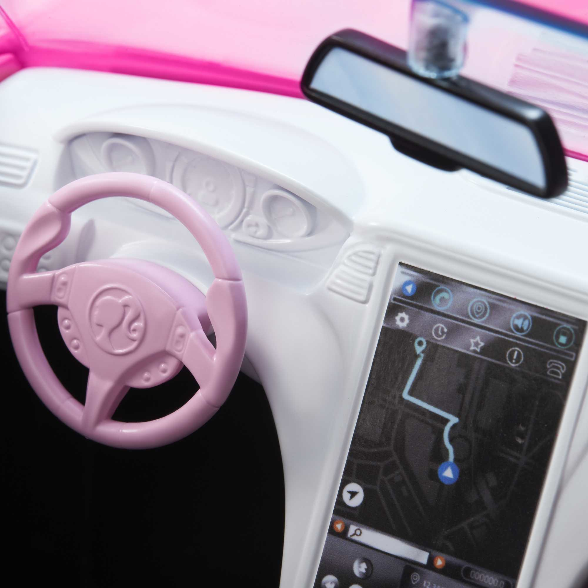 Nahaufnahme des Barbie-Auto-Innenraums. Pinkes Lenkrad, weißes Armaturenbrett mit Bildschirm.
