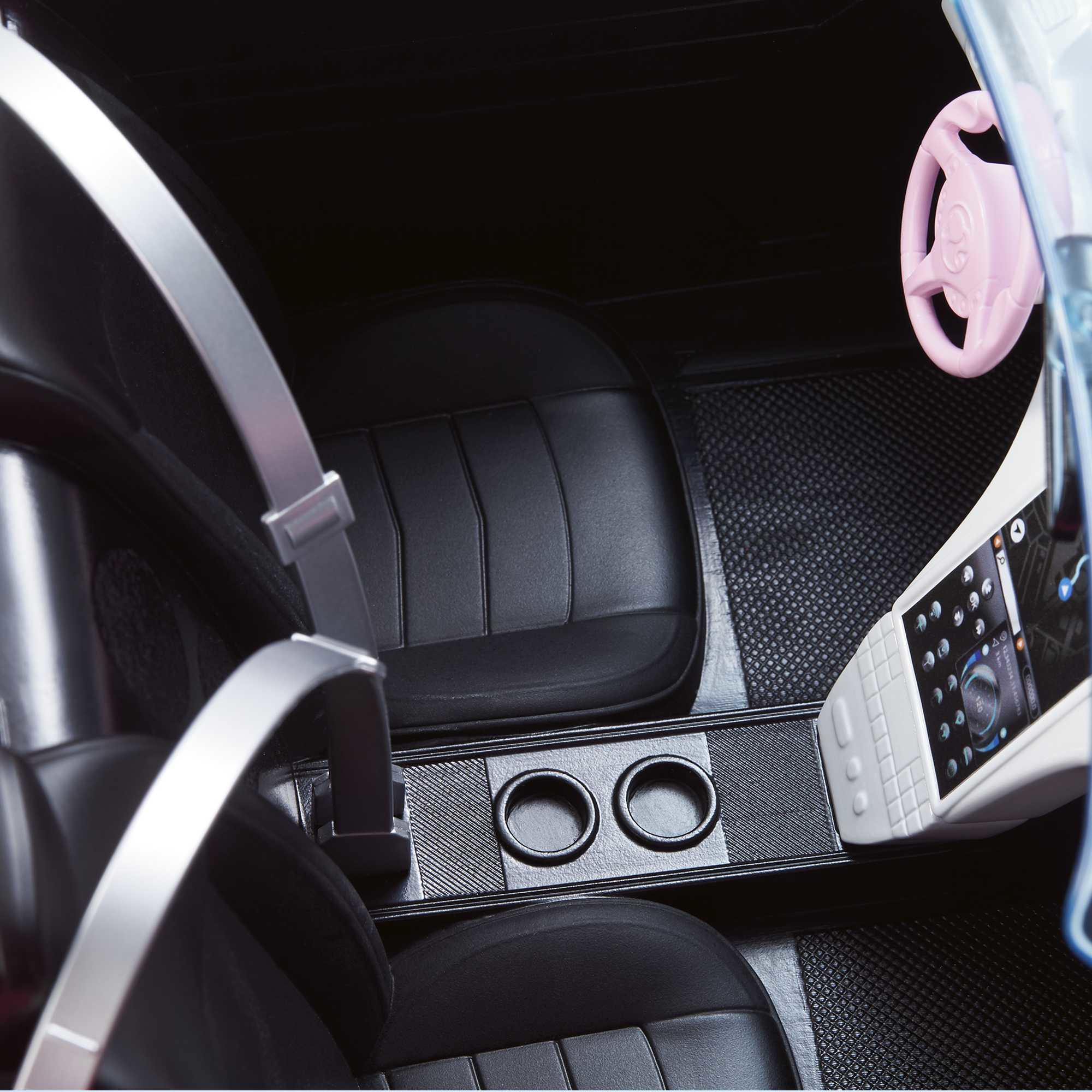 Innenraum eines Spielzeugautos, schwarze Sitze, rosa Lenkrad und Mittelkonsole mit Getränkehaltern.