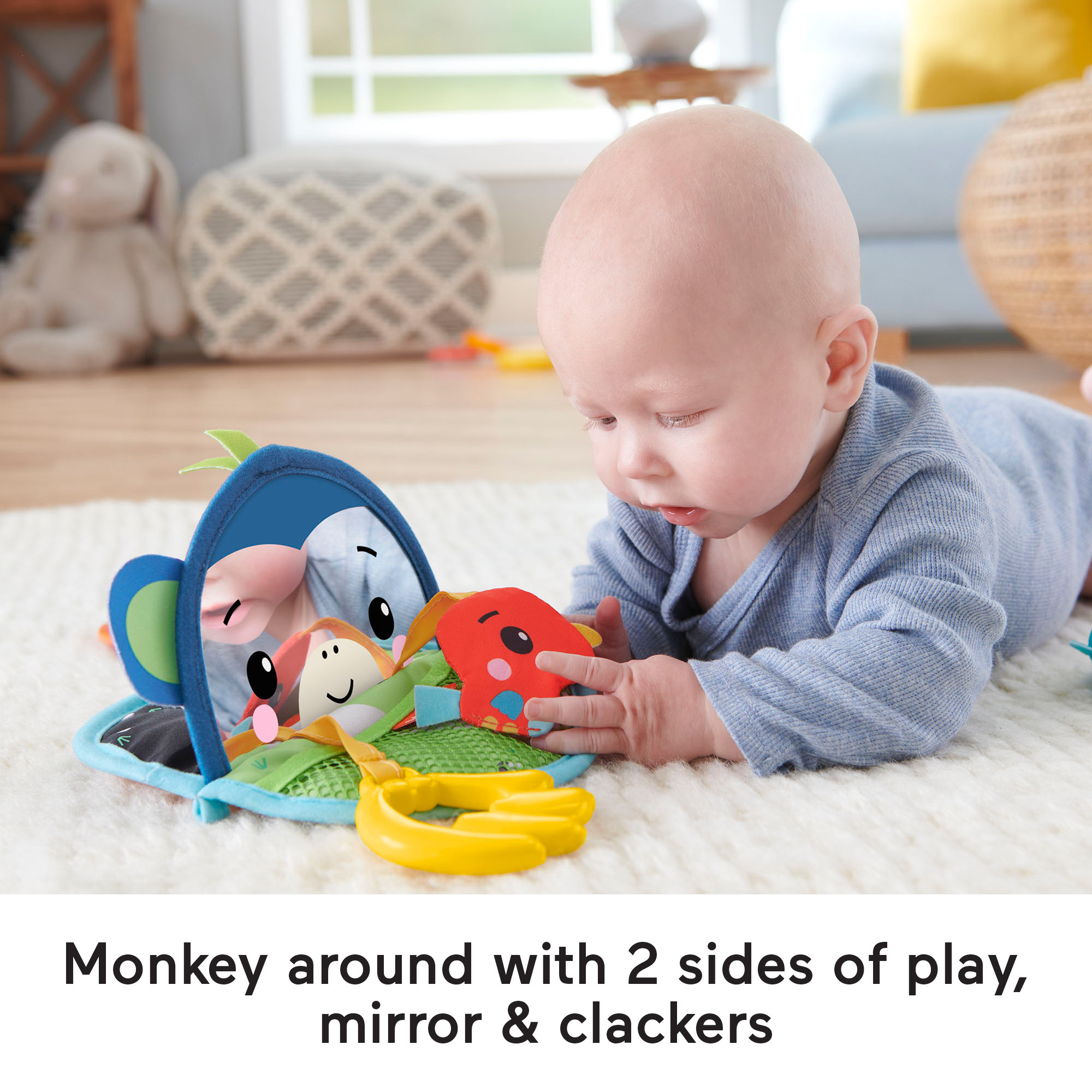 Niemowlę patrzy na niebiesko-białą zabawkę z lusterkiem i dwoma zabawkami na białym dywanie.