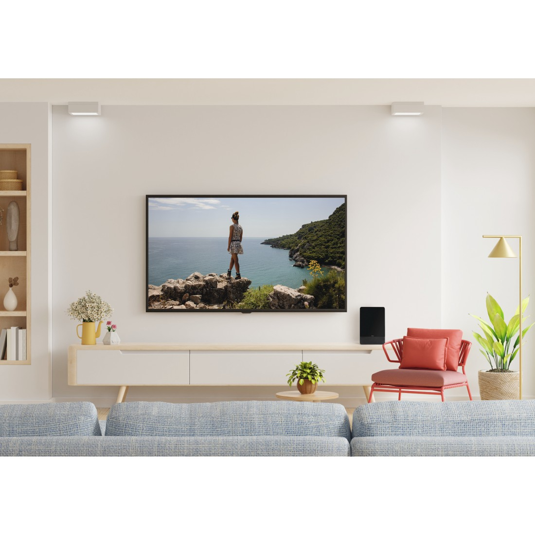 Soggiorno con TV a parete, divano, sedia e decorazioni. Vista di una scena costiera sullo schermo.