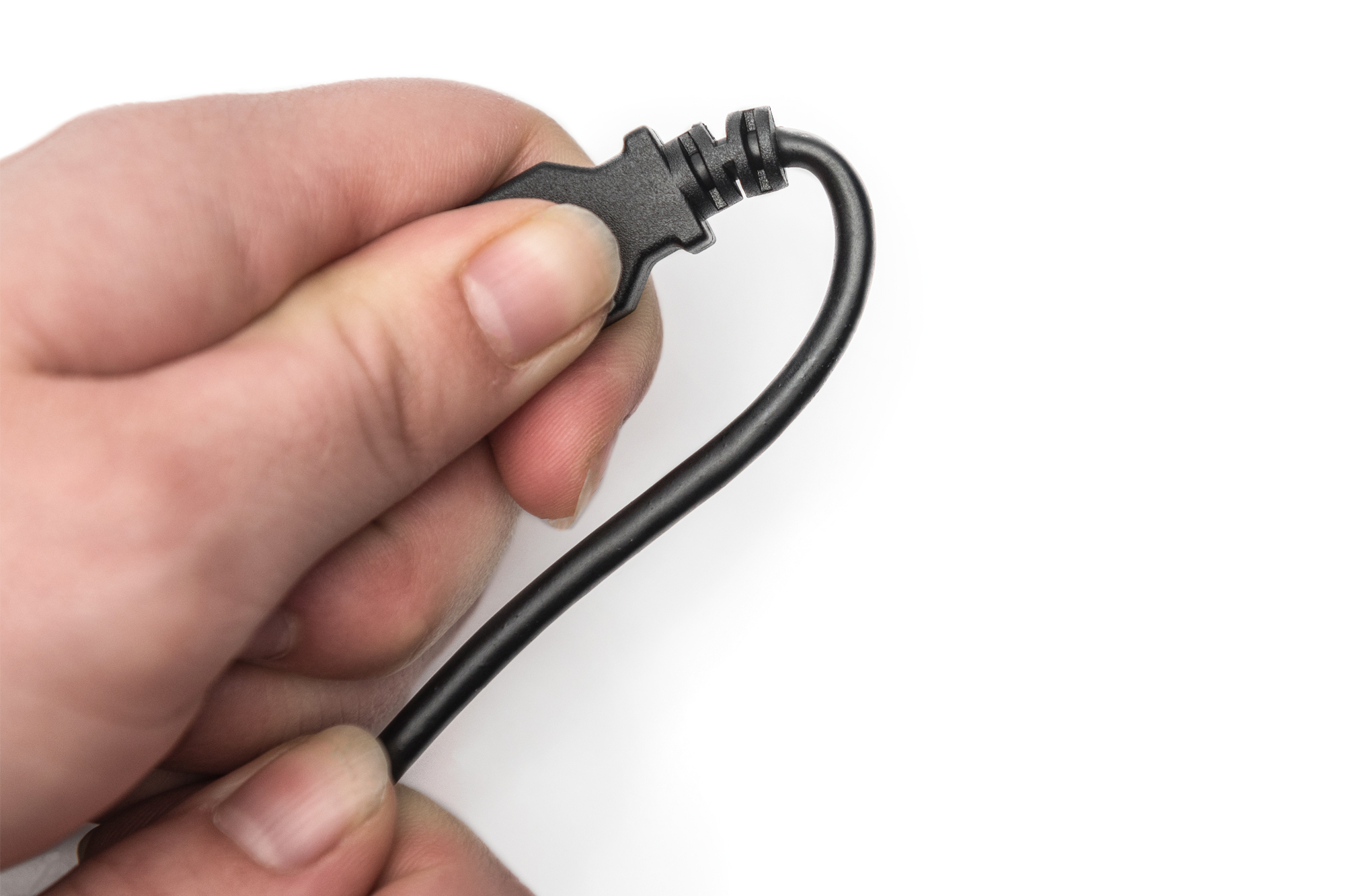 Ręka trzymająca czarny kabel z wtyczką na białym tle.