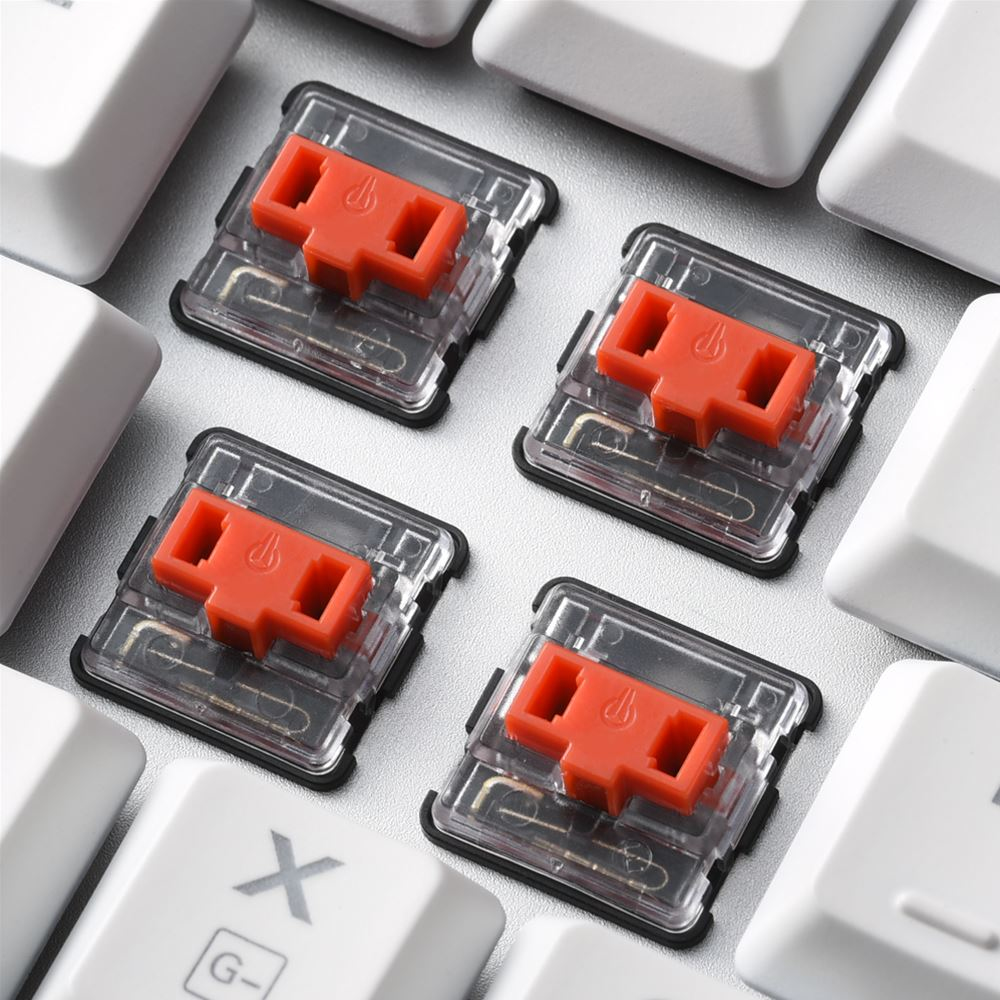 Cuatro interruptores de teclado mecánico rojos, primer plano. Las teclas blancas rodean los interruptores.