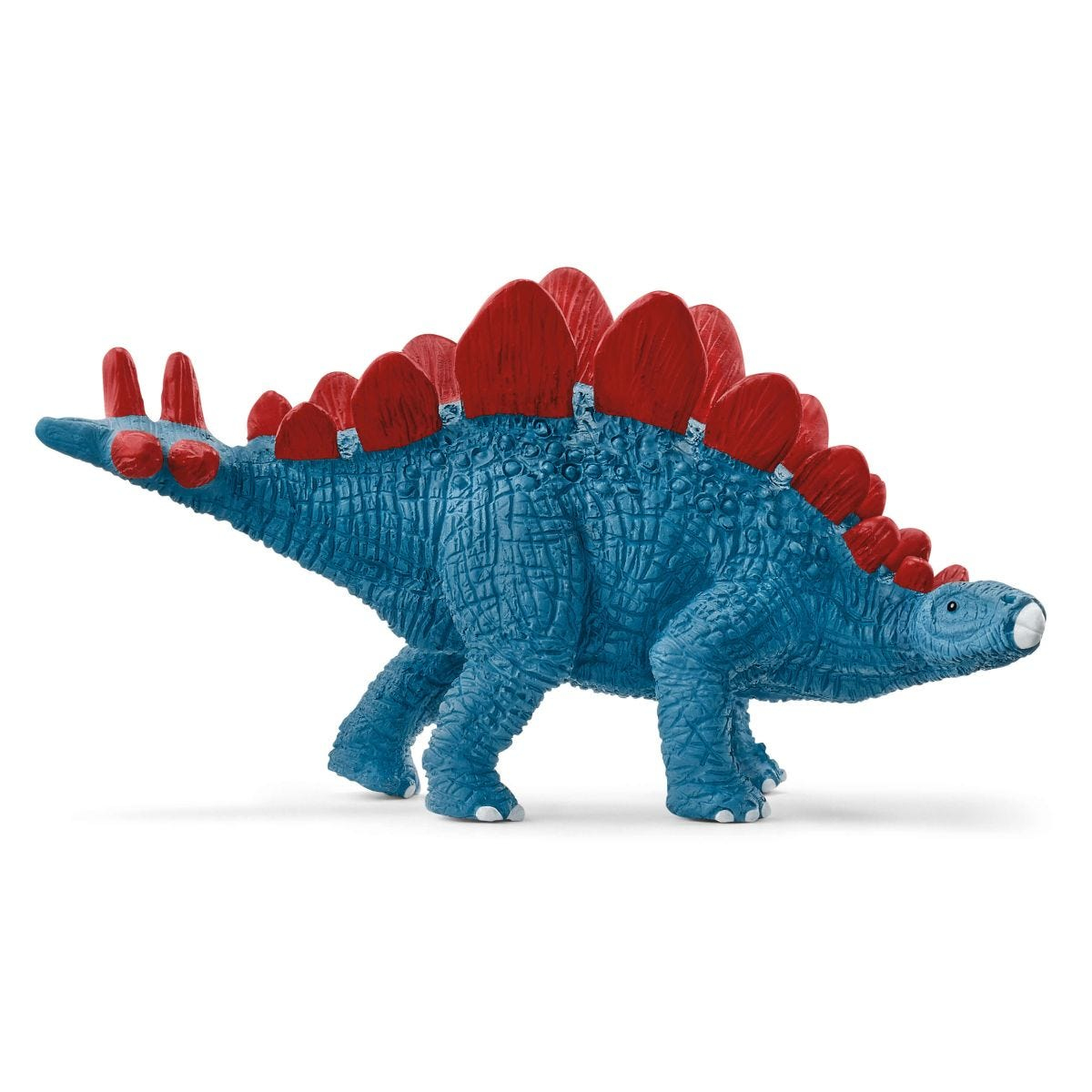 Ein blaues Dinosaurierspielzeug mit roten Platten auf dem Rücken, das auf einer weißen Oberfläche steht.