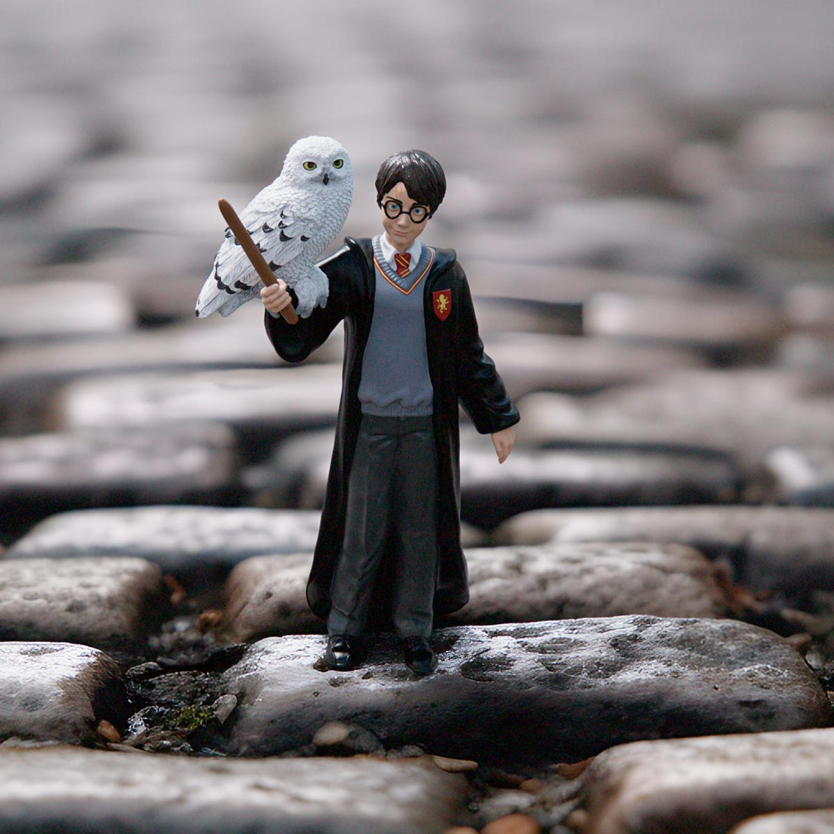 Figura di Harry Potter con gufo, con bacchetta, su pavé.