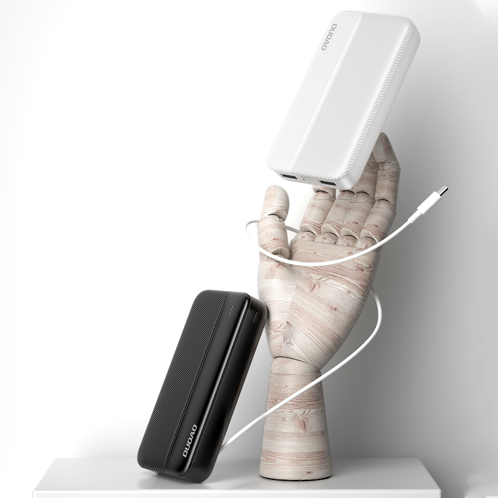 Zwei Powerbanks, schwarz und weiß, mit einer Holzhand, die sie hält, und einem Ladekabel.