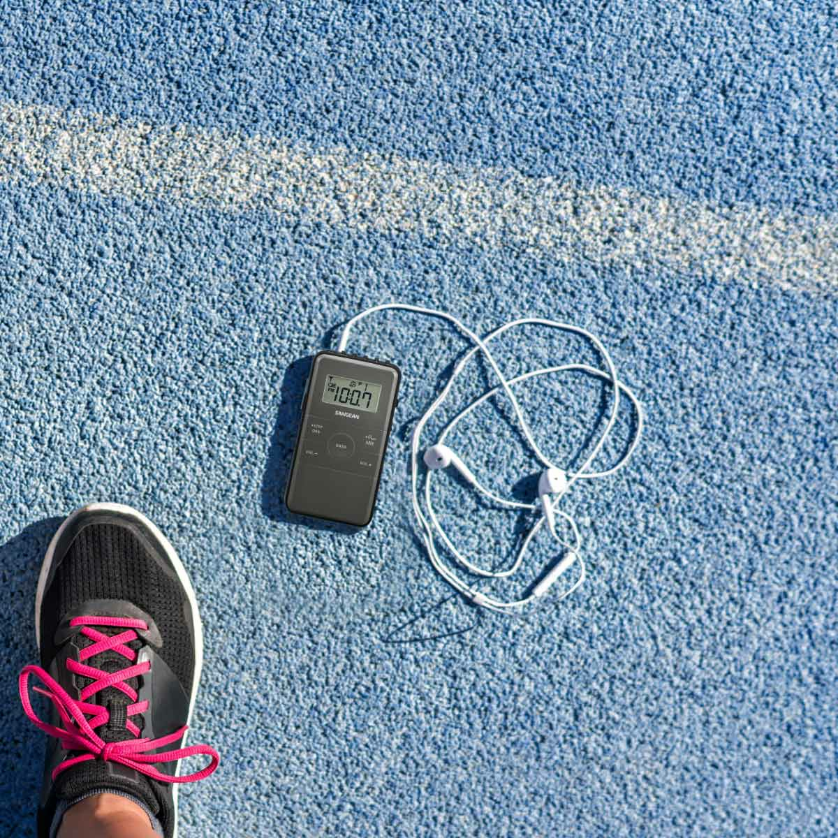 But do biegania, czarny, różowe sznurowadła, z odtwarzaczem MP3 i słuchawkami na niebieskim torze.