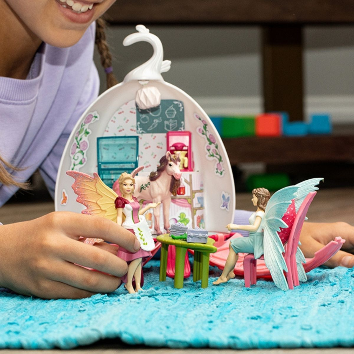 Ein Feenspielset mit Puppen, einem Pferd und Möbeln auf einer blauen Spielmatte.