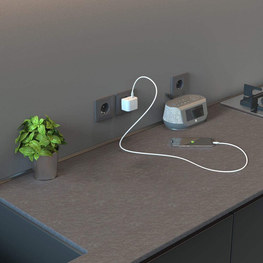 Blat kuchenny z rośliną, gniazdkami elektrycznymi, ładującym się telefonem i głośnikiem smart.