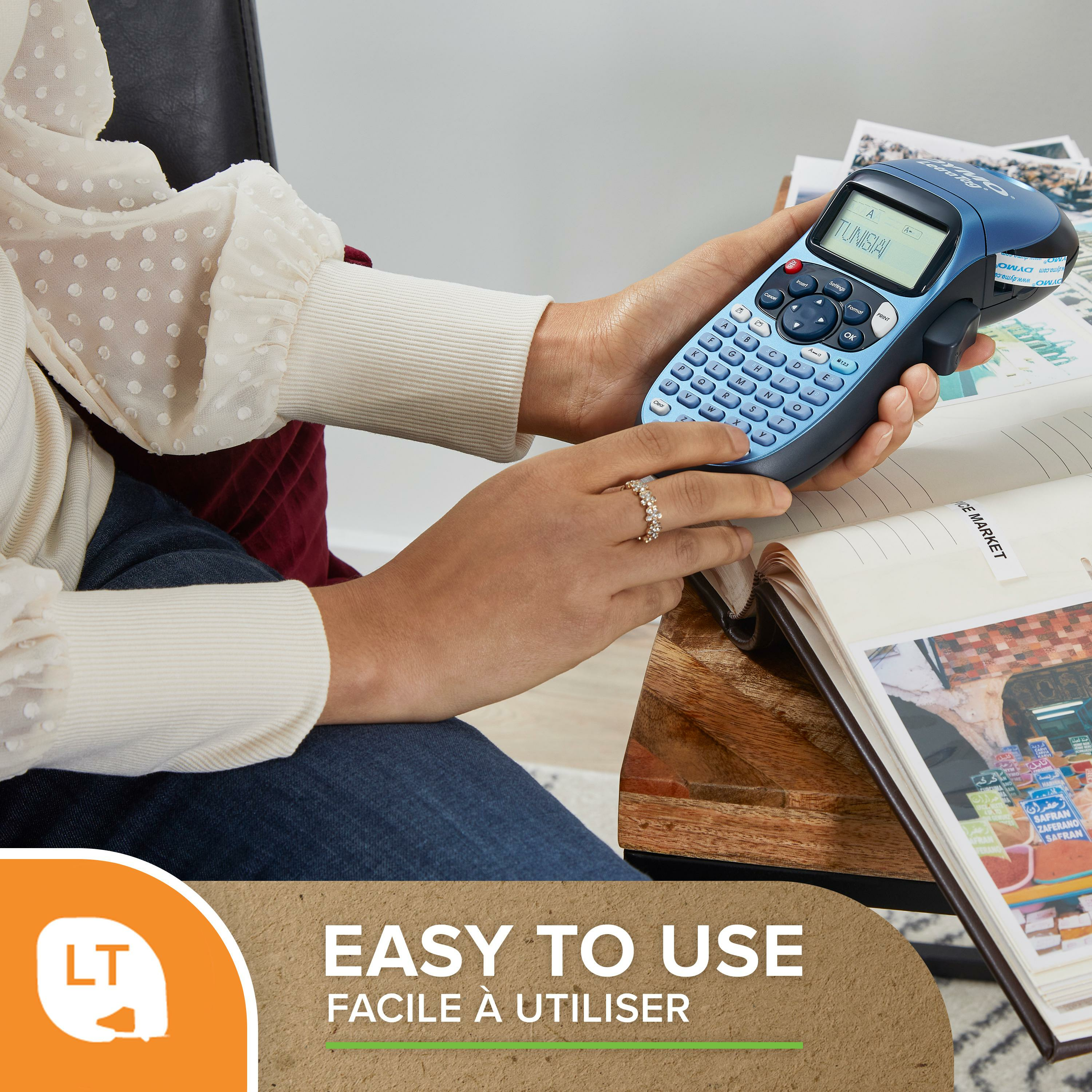 Osoba używająca niebieskiej etykieciarki. Tekst brzmi 'TUNISIA'. Zeszyt i reklama w tle.