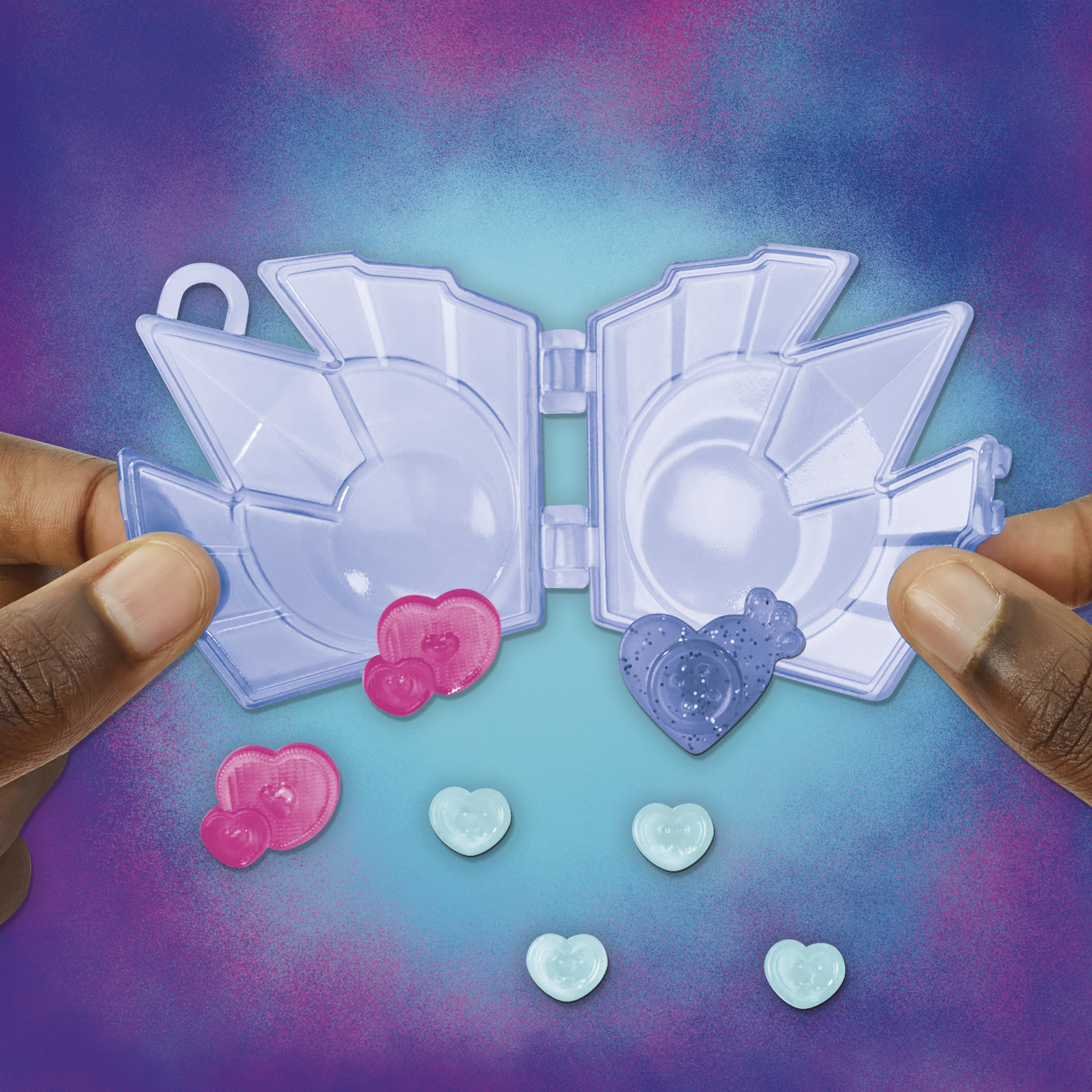 Mani che tengono un giocattolo di plastica con cuori e un contenitore a forma di cuore su sfondo viola.