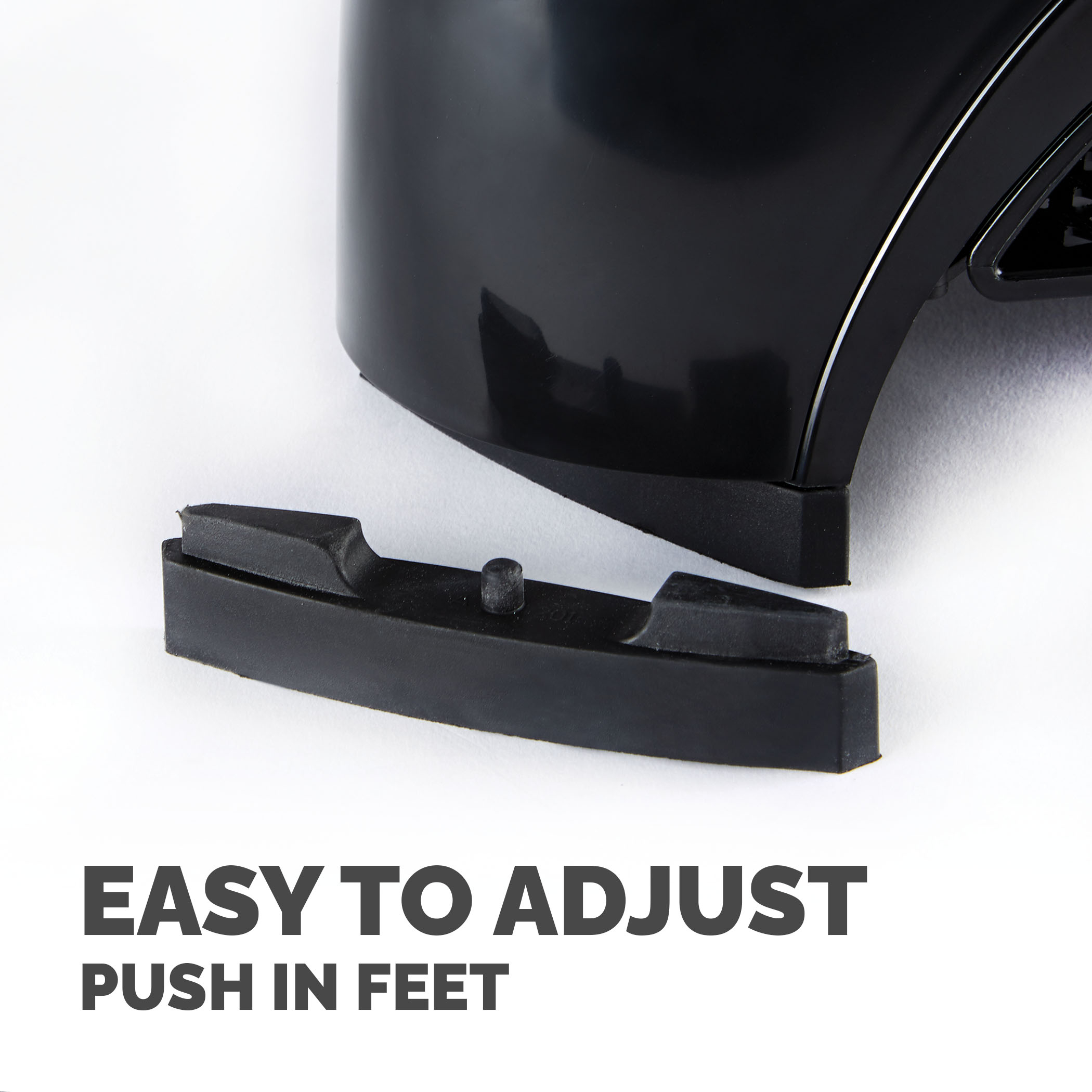 Czarny obiekt z odłączoną stopą. Tekst brzmi 'EASY TO ADJUST PUSH IN FEET'. Obiekt znajduje się na białej powierzchni.