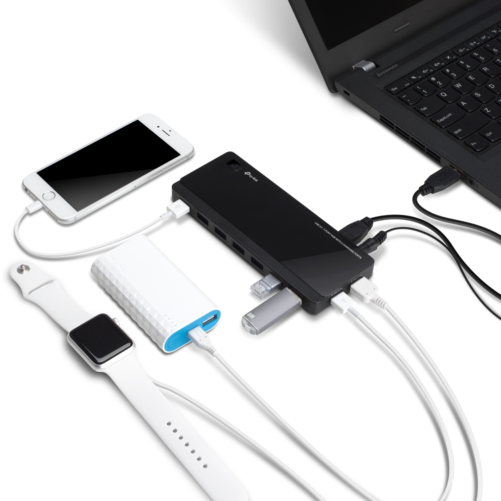 Ein Laptop, Telefon, Uhr und Ladehub mit Kabeln und angeschlossenen Geräten, alles auf weißem Grund.