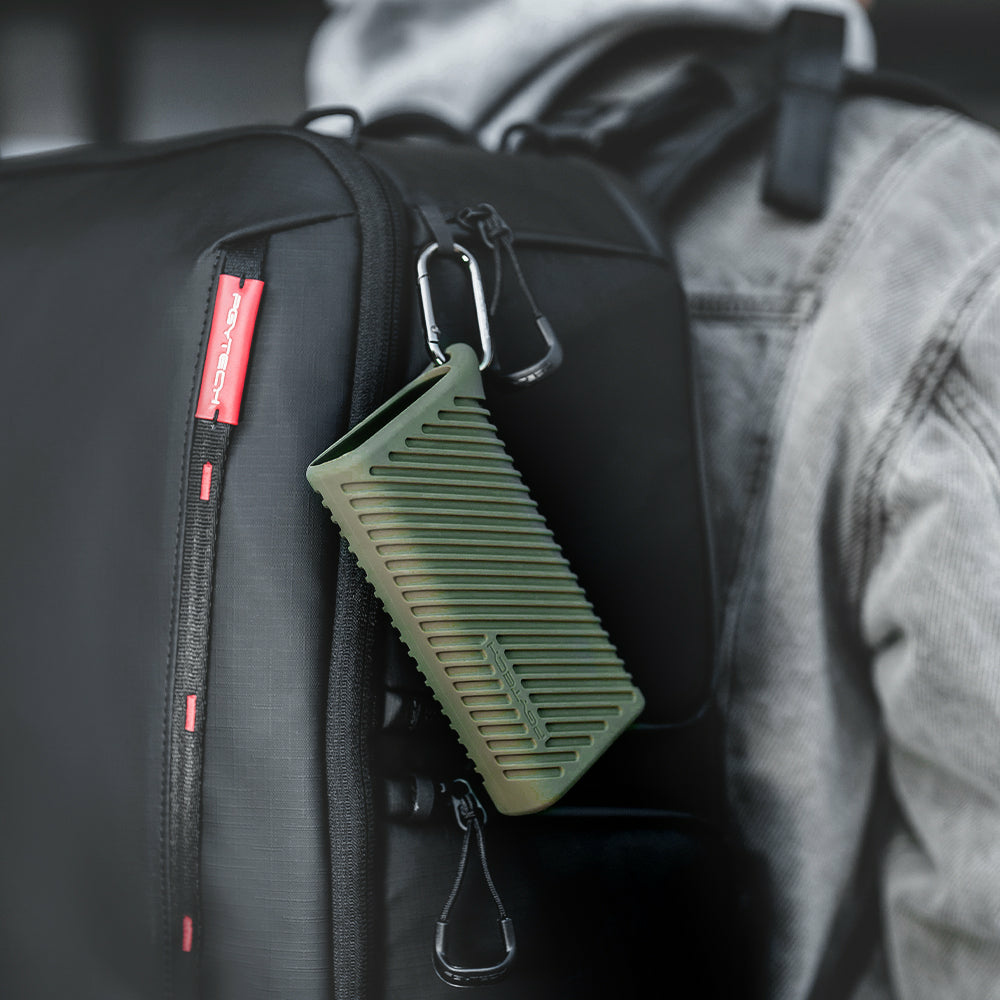 Czarny plecak z zielonym etui przymocowanym za pomocą karabińczyka. Etui jest żebrowane.