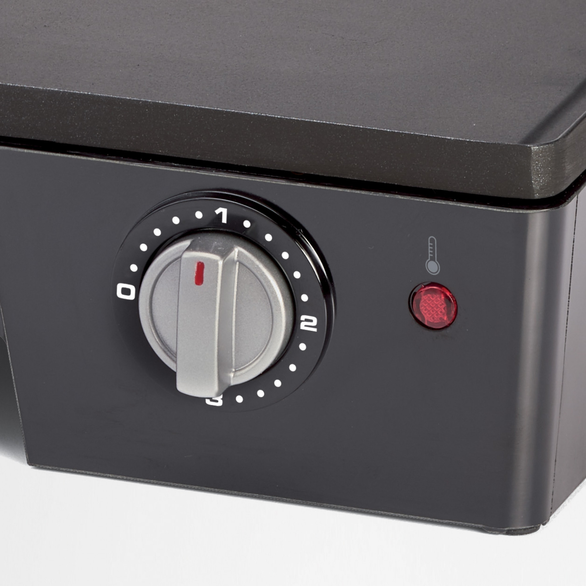 Close-up of a black appliance control panel with a dial and a red light.