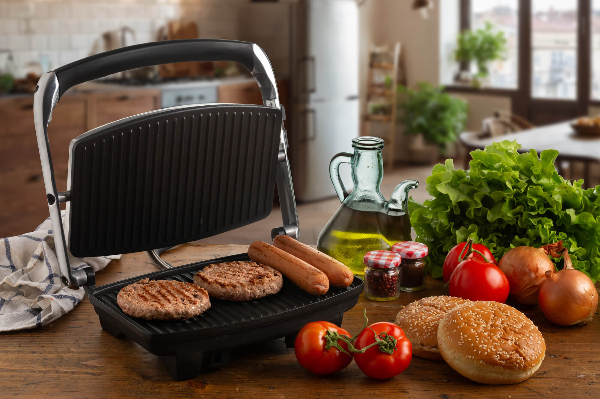 Grill mit Burgern und Hotdogs. Tomaten, Zwiebeln und anderes Essen liegen auf dem Tisch.