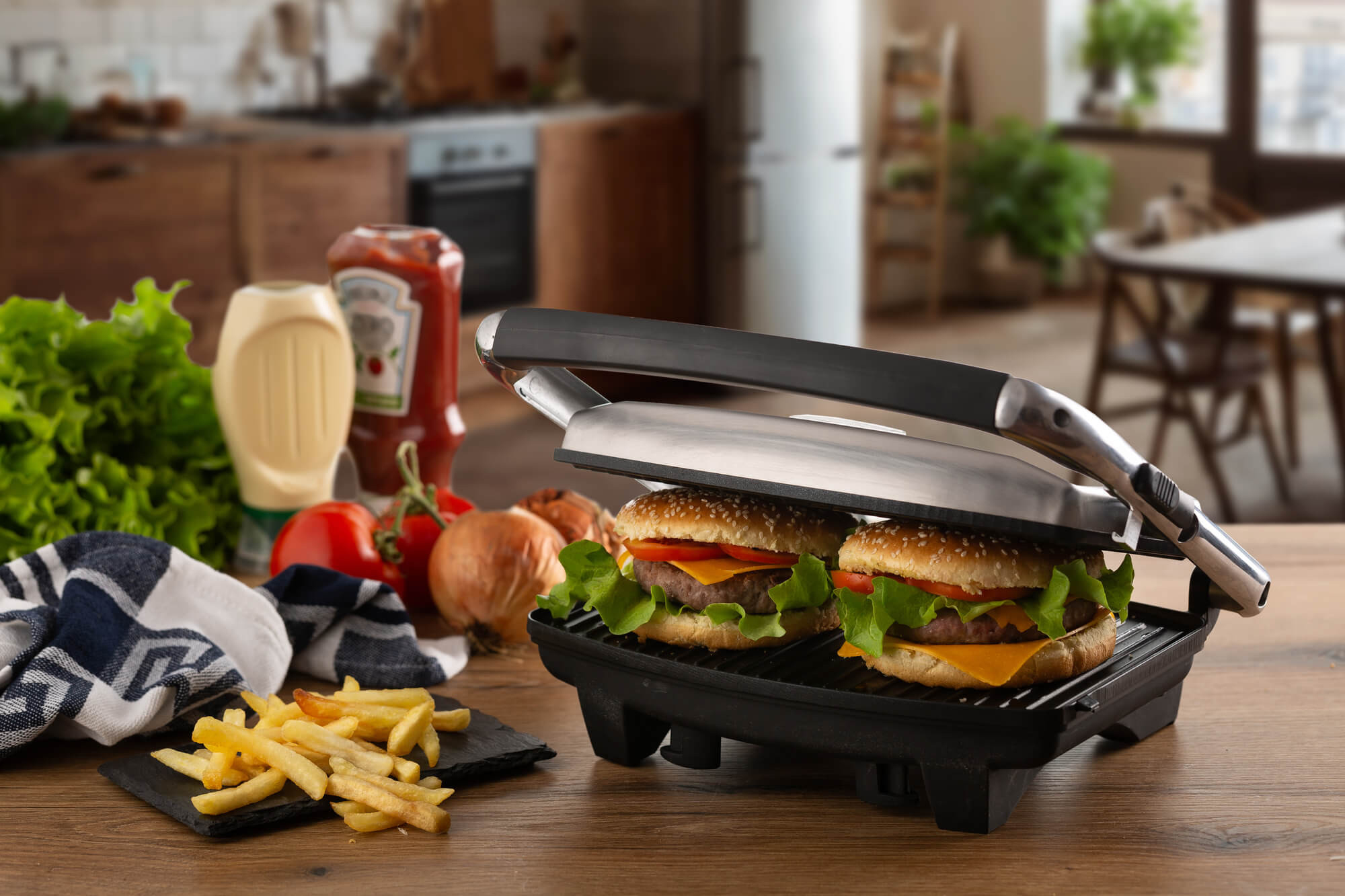 Burger auf einem Grill, mit Pommes, Ketchup und Gemüse auf einem Holztisch.