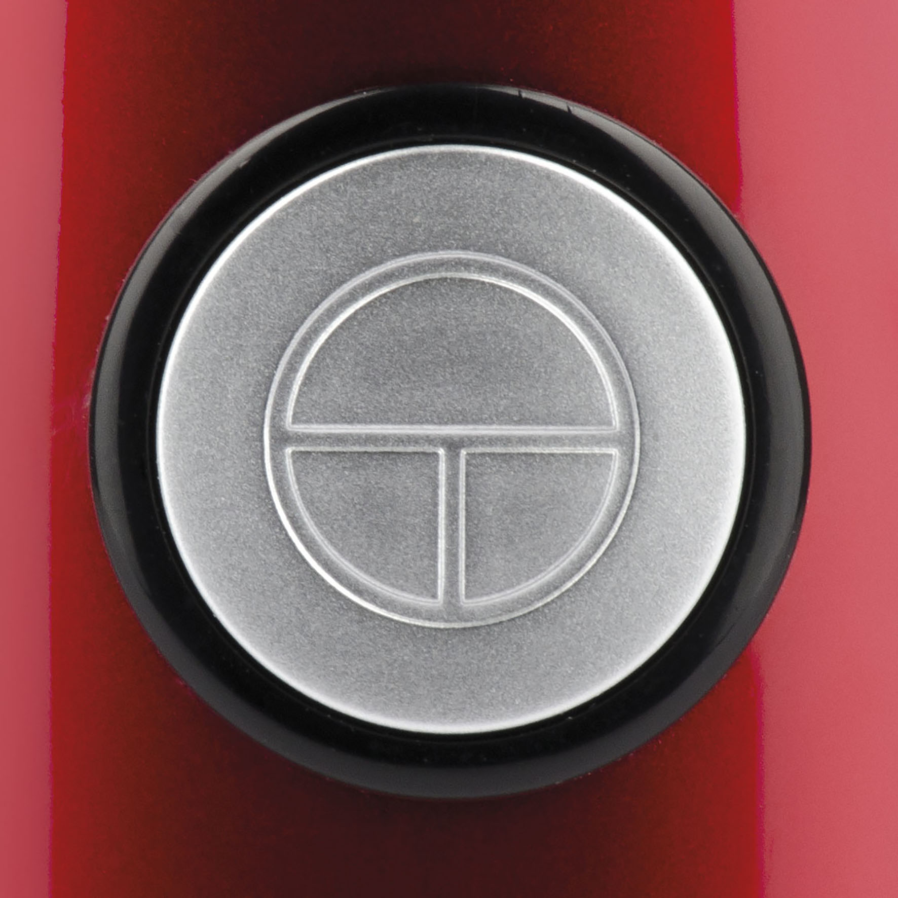 Pulsante rosso con centro argentato e bordo nero.