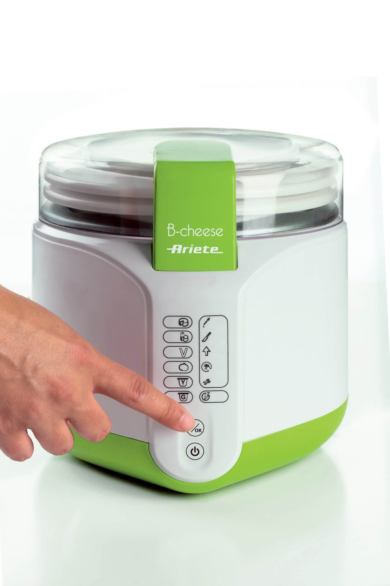 Ręka osoby naciska przycisk na białej i zielonej maszynie do produkcji sera B-cheese.