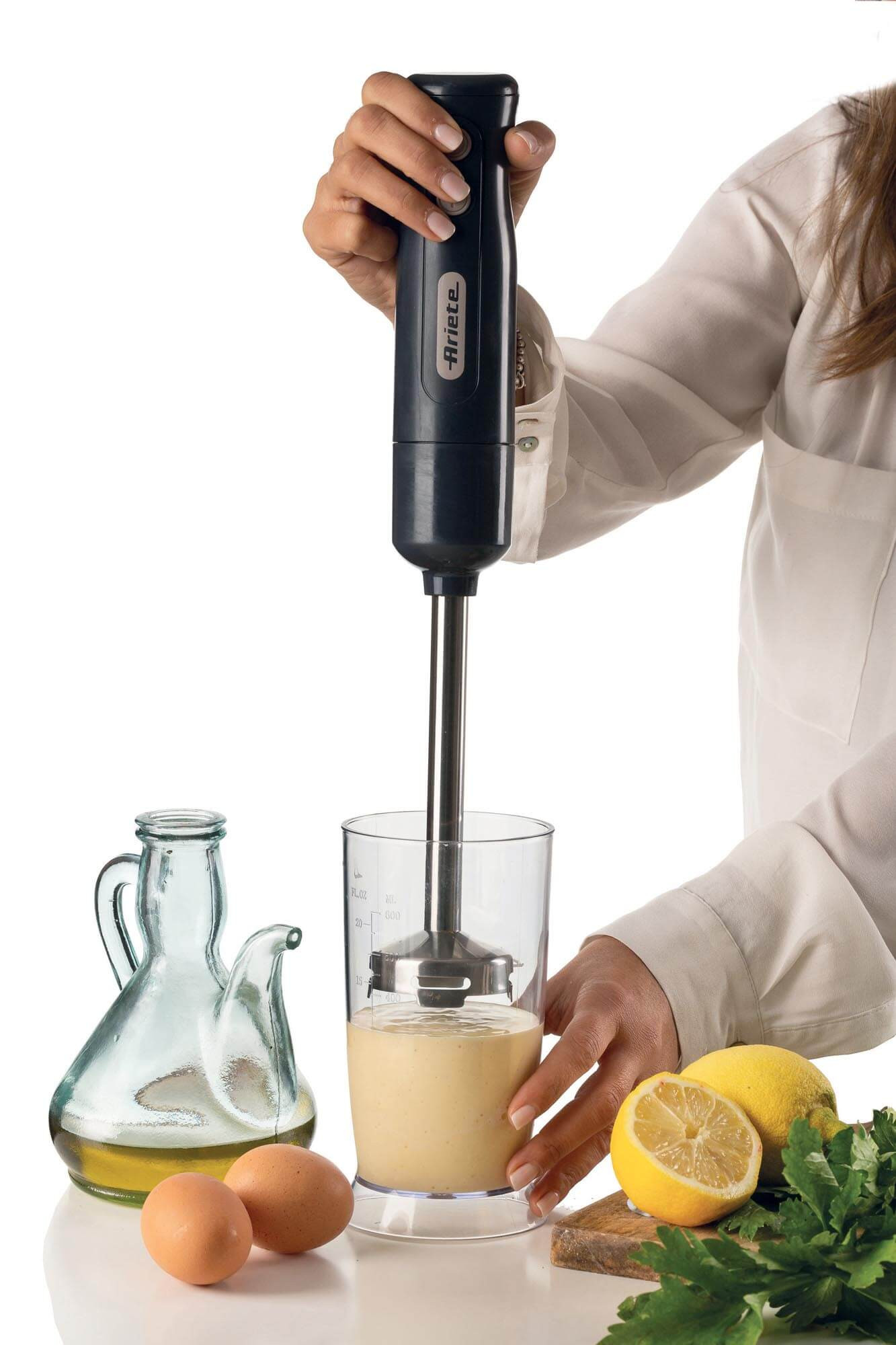 Kobieta miksuje składniki blenderem ręcznym.