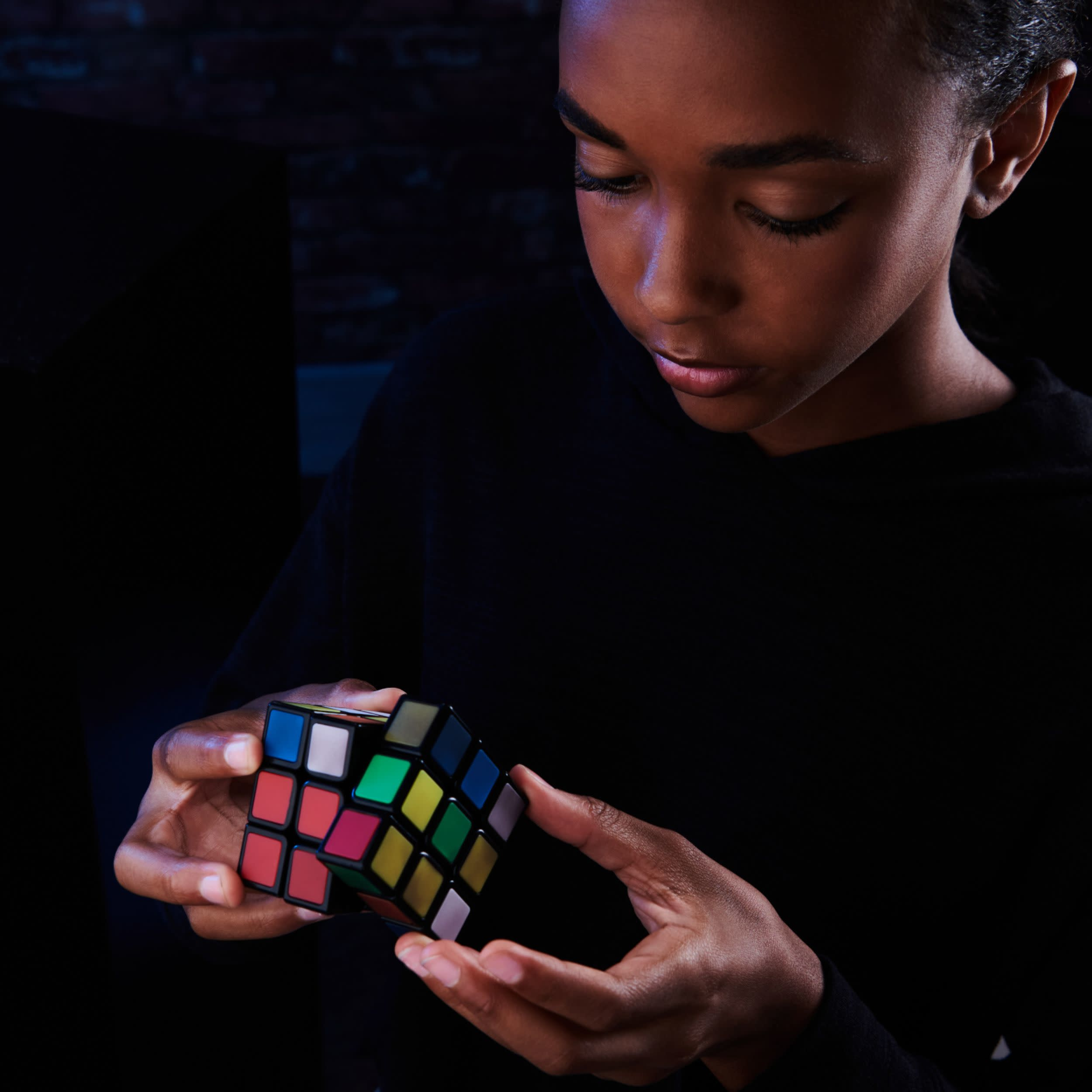 Una ragazza che risolve un cubo di Rubik. È concentrata e guarda il cubo.