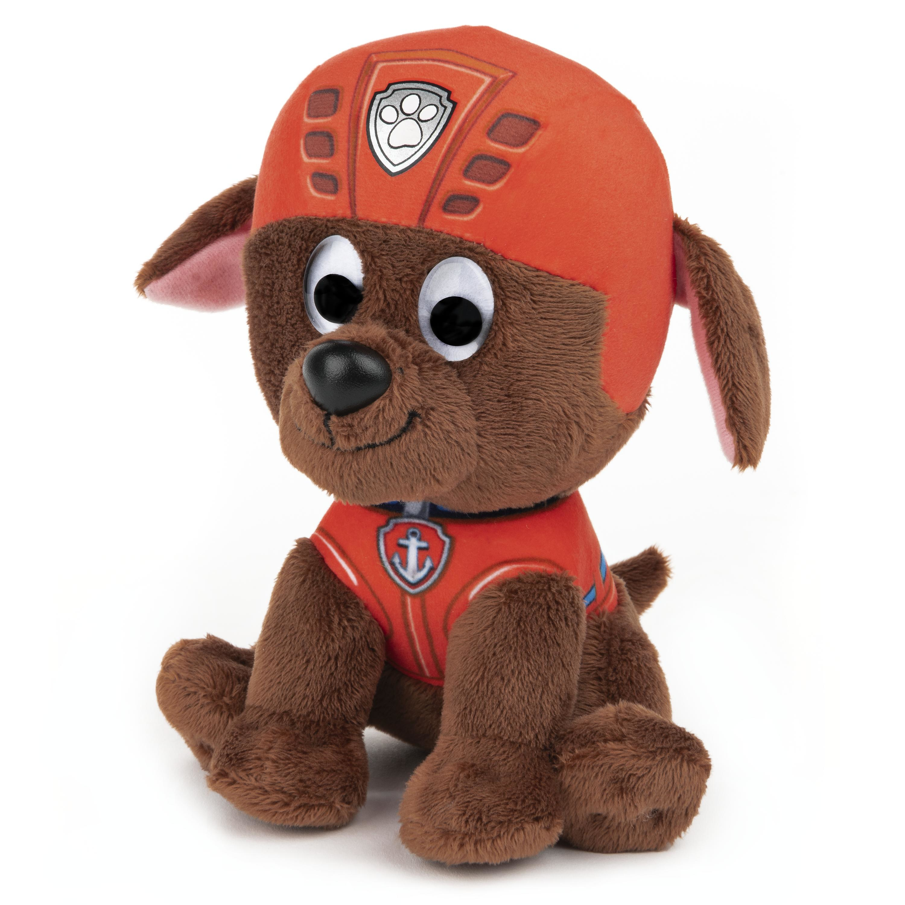 Braunes Plüschtier eines Hundes mit orangefarbenem Helm und Weste, sitzt auf weißer Fläche.