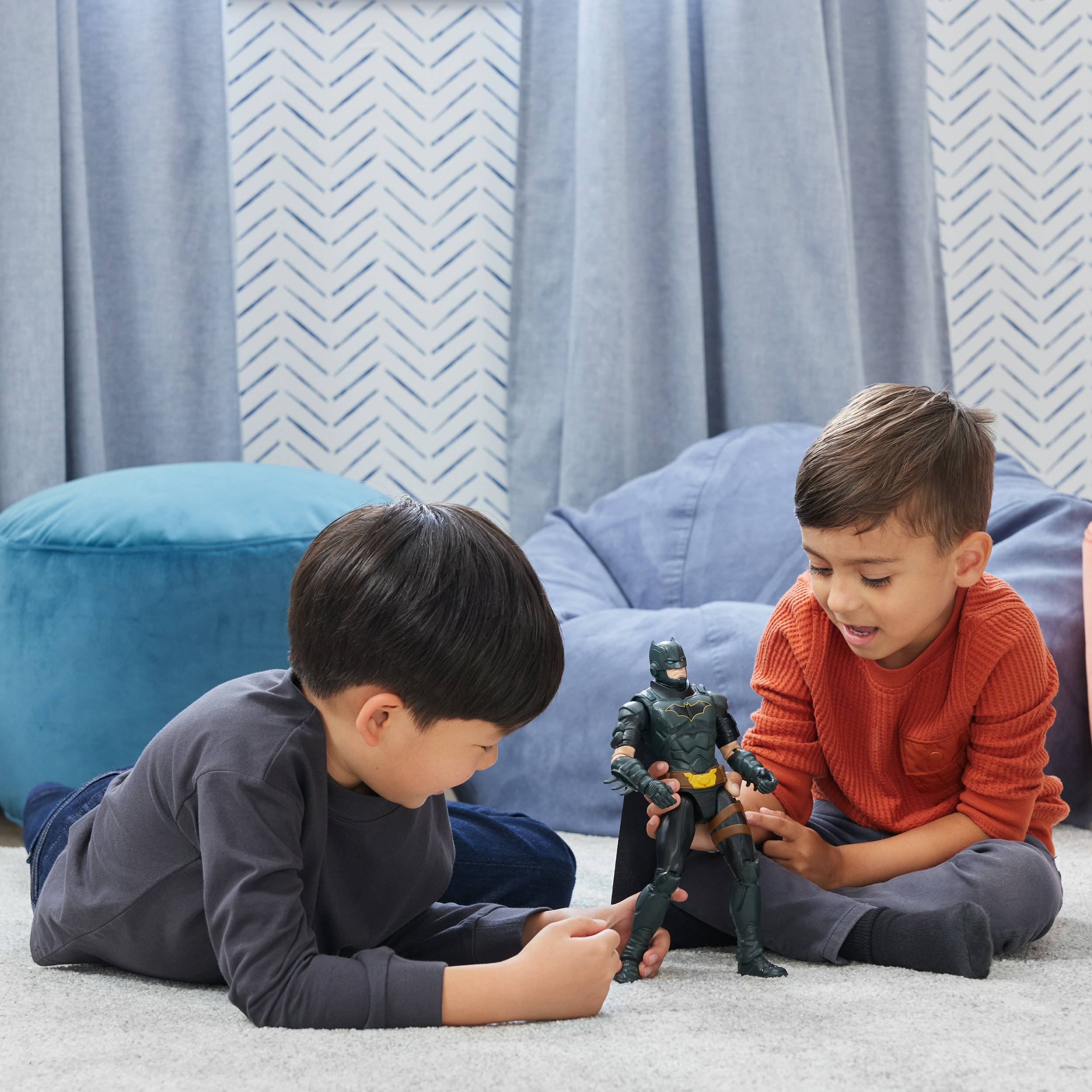 Zwei Jungen spielen mit einer Batman-Spielzeugfigur. Das Spielzeug ist schwarz mit gelben Akzenten.