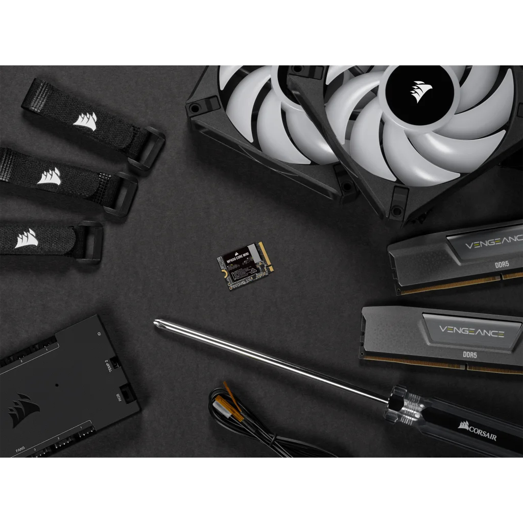 Komponenty komputera, w tym wentylator, kości RAM, dysk SSD i śrubokręt na czarnej powierzchni.