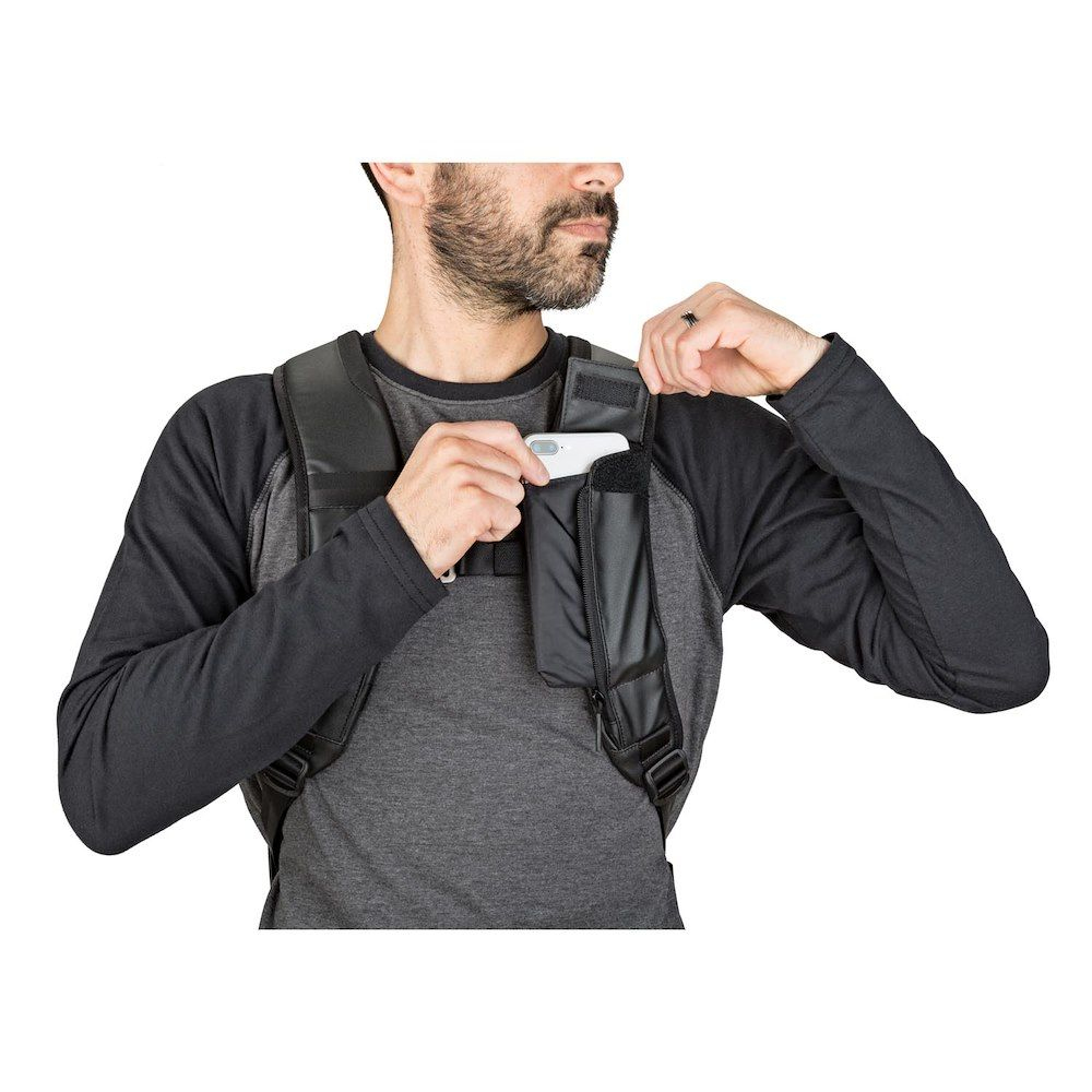 Ein Mann mit einer Brusttasche und einem Telefon in der Tasche. Der Mann hat einen Bart und trägt ein graues Hemd.