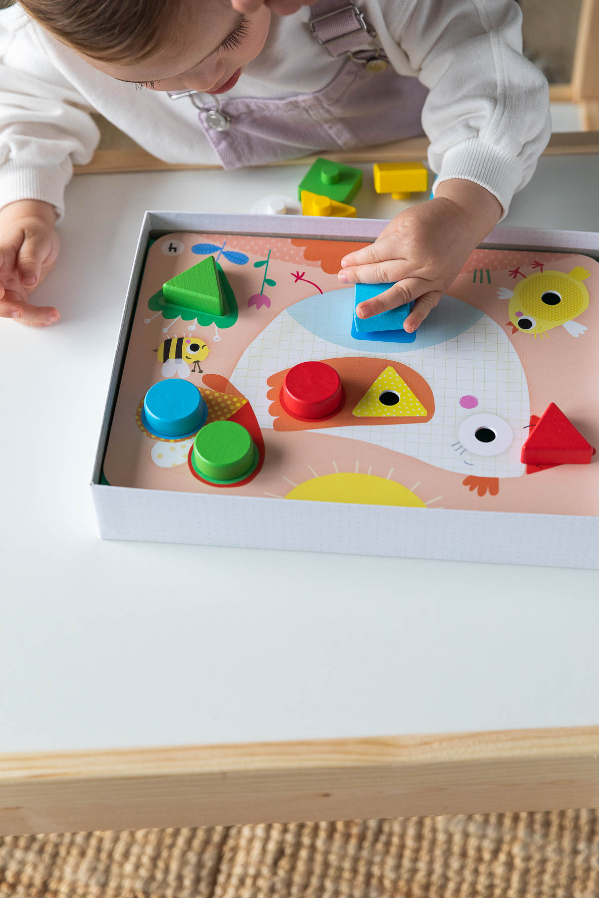Un bambino piccolo che gioca con un giocattolo per l'ordinamento delle forme. Varie forme colorate.