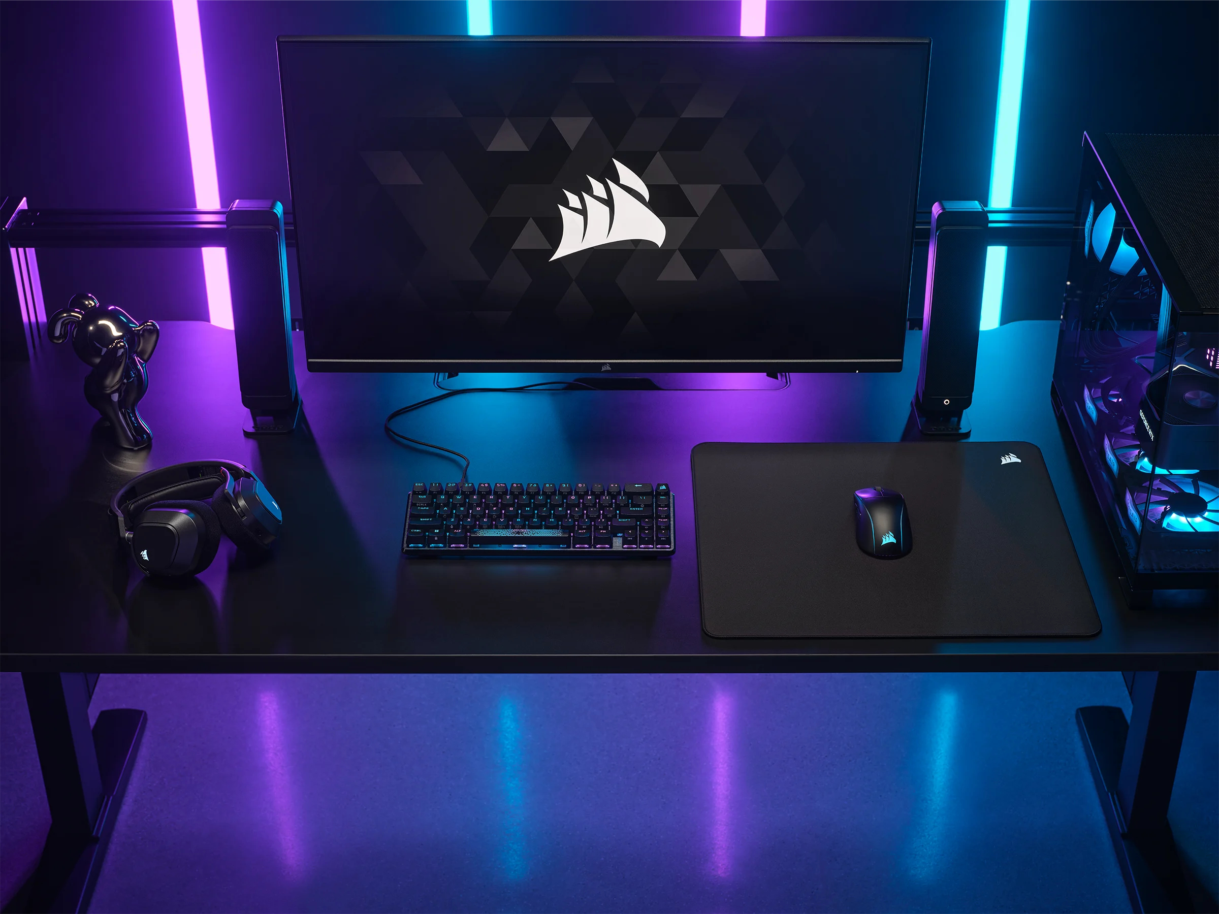 Czarny stół z konfiguracją komputera. Zawiera monitor, głośniki, klawiaturę i mysz.