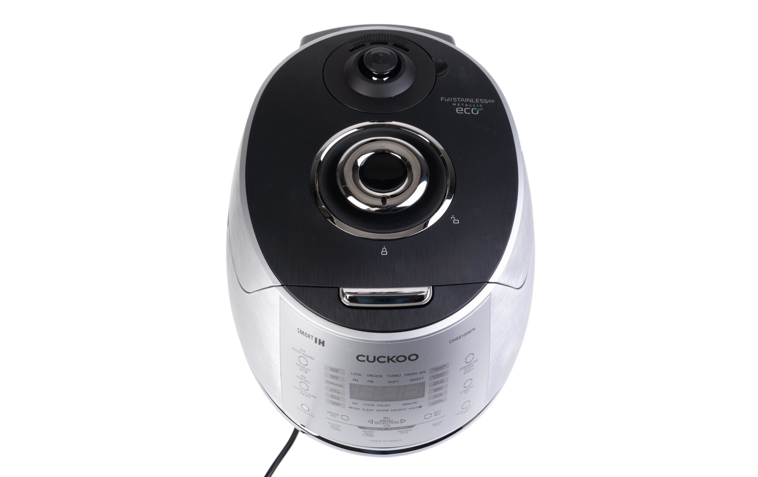 Ryżowar, widok z góry. Metaliczny srebrny i czarny design. Panel sterowania widoczny. Białe tło.