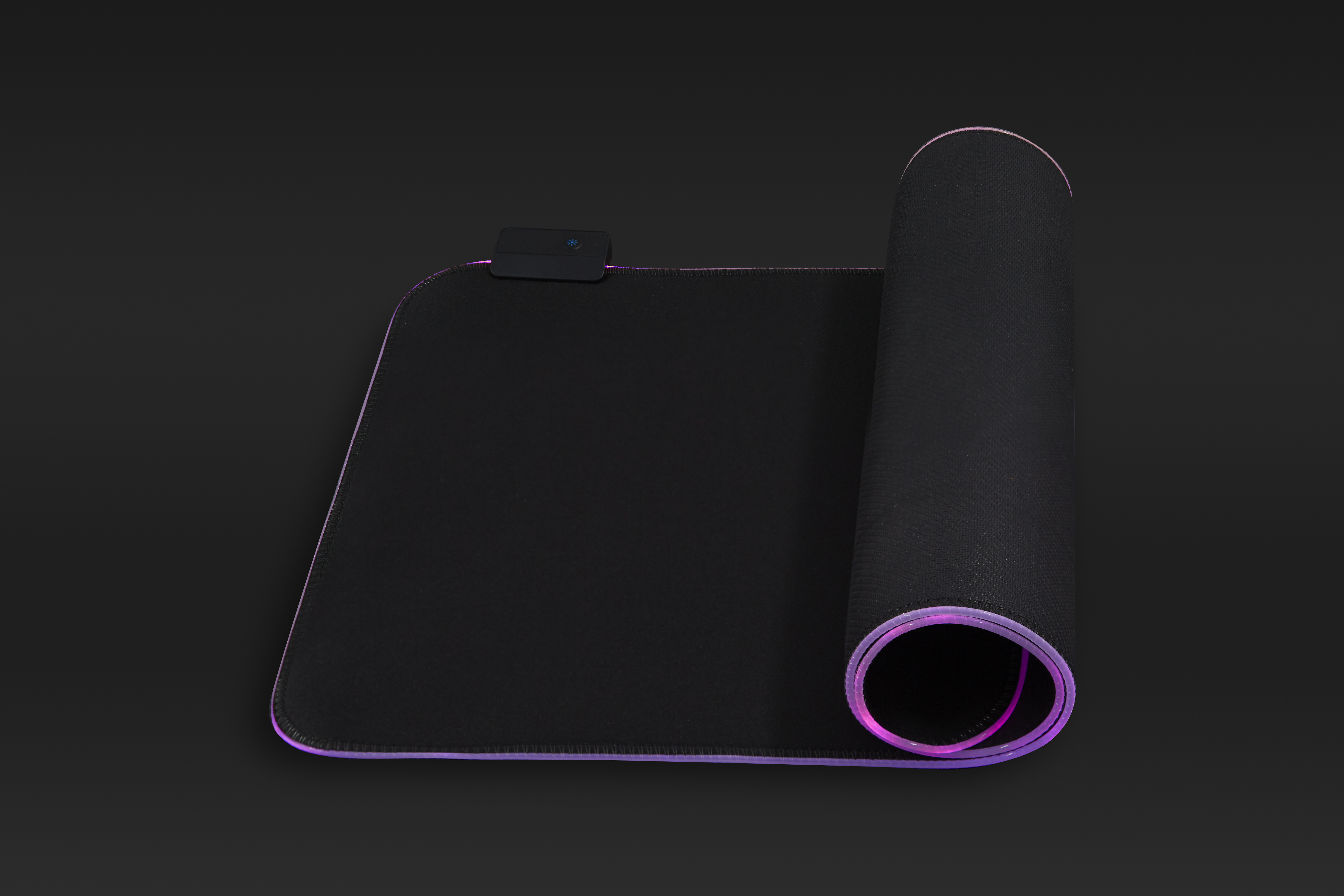 Czarna podkładka pod mysz zwinięta. Fioletowe oświetlenie krawędzi LED. Ciemne tło. Zdjęcie produktu.
