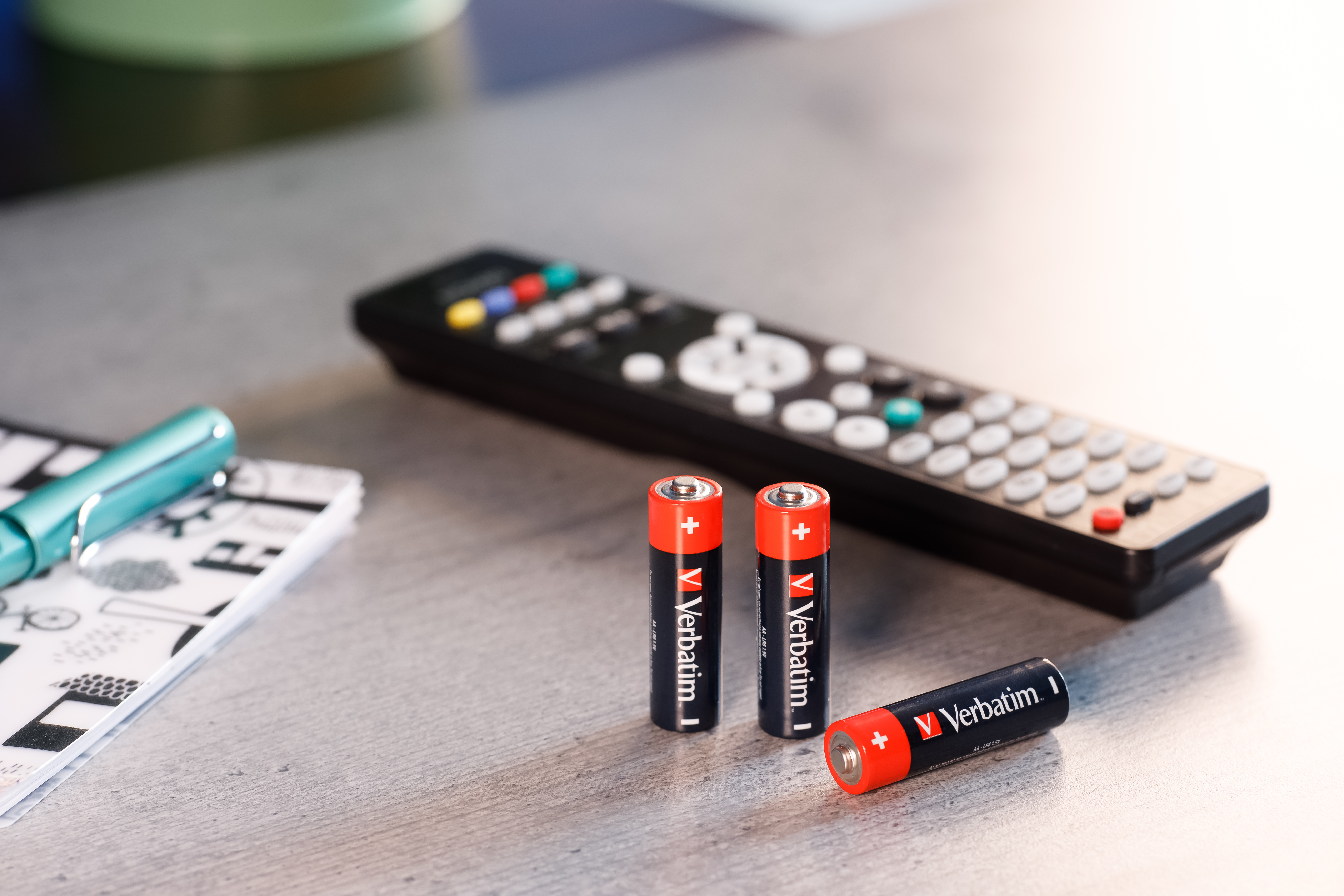 Pilot, baterie, długopis i notatnik na szarym drewnianym stole. Miękkie oświetlenie, zbliżenie.