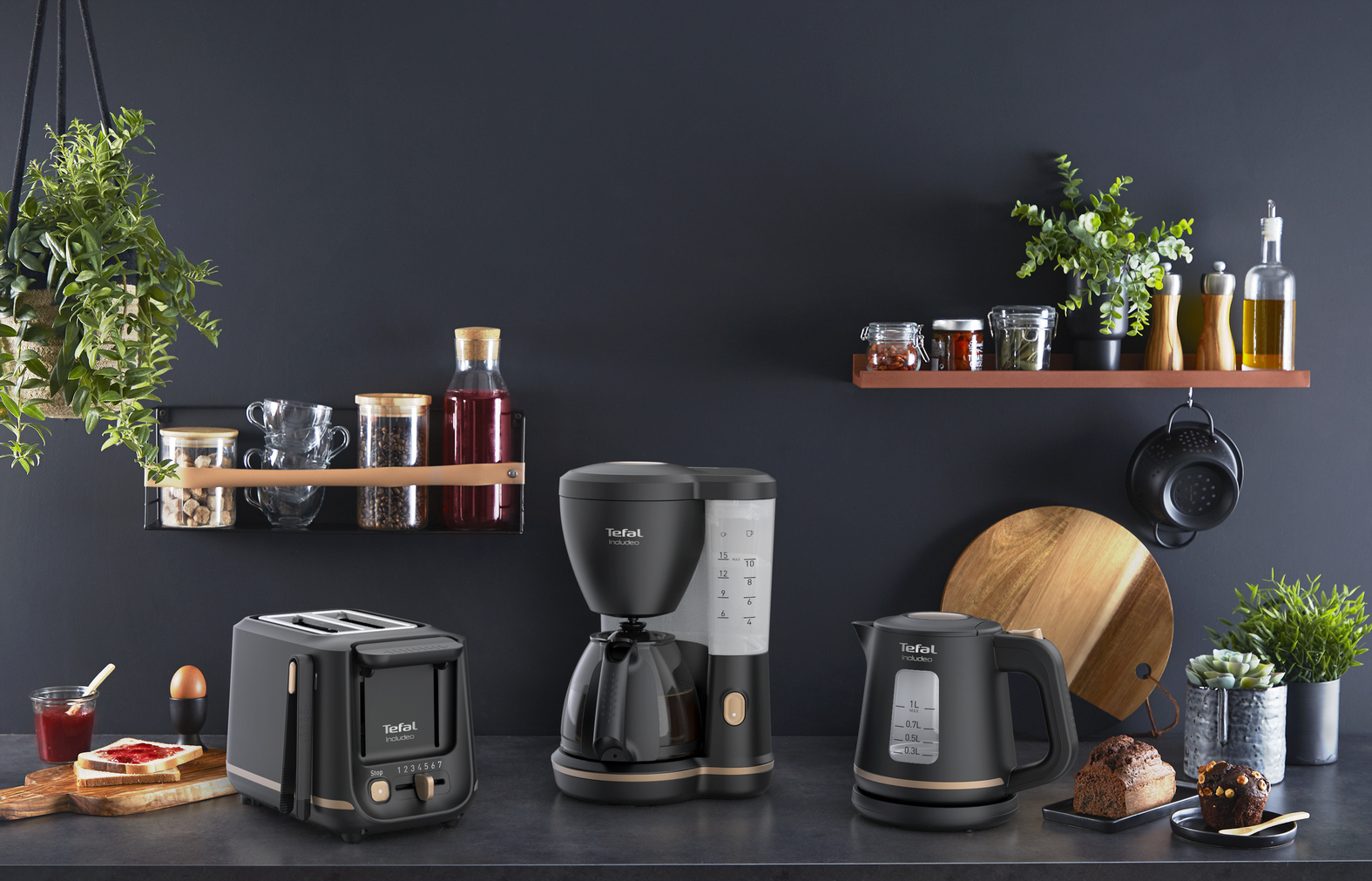 Sprzęty kuchenne na ciemnym blacie. Toster, ekspres do kawy i czajnik. Ciemne tło.