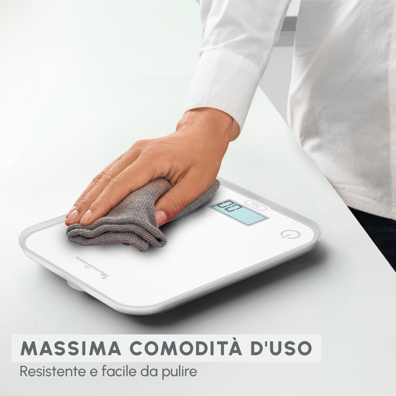Ręka wycierająca białą wagę szarą szmatką. Tekst: Maksymalna łatwość użytkowania.