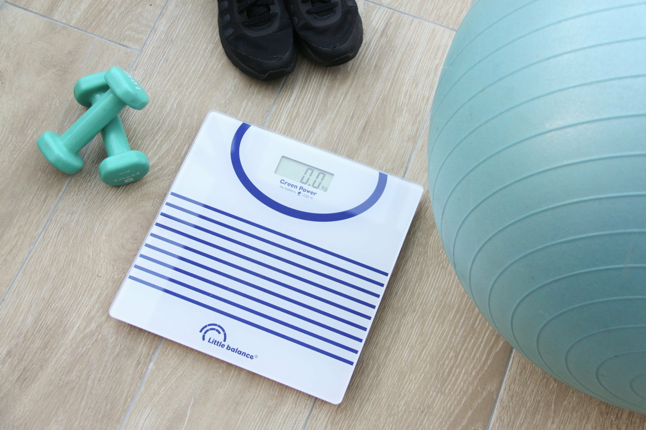 Waga, hantle i piłka do ćwiczeń na drewnianej podłodze, motyw fitness.