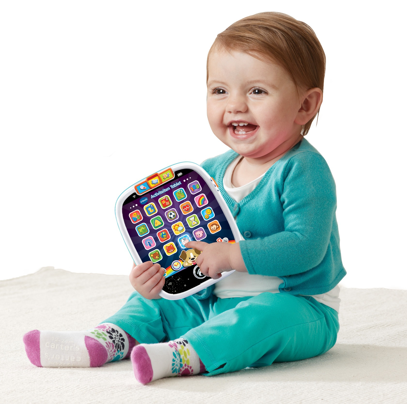 Lachendes Baby mit tealfarbener Strickjacke, Hose und gemusterten Socken, hält Tablet.