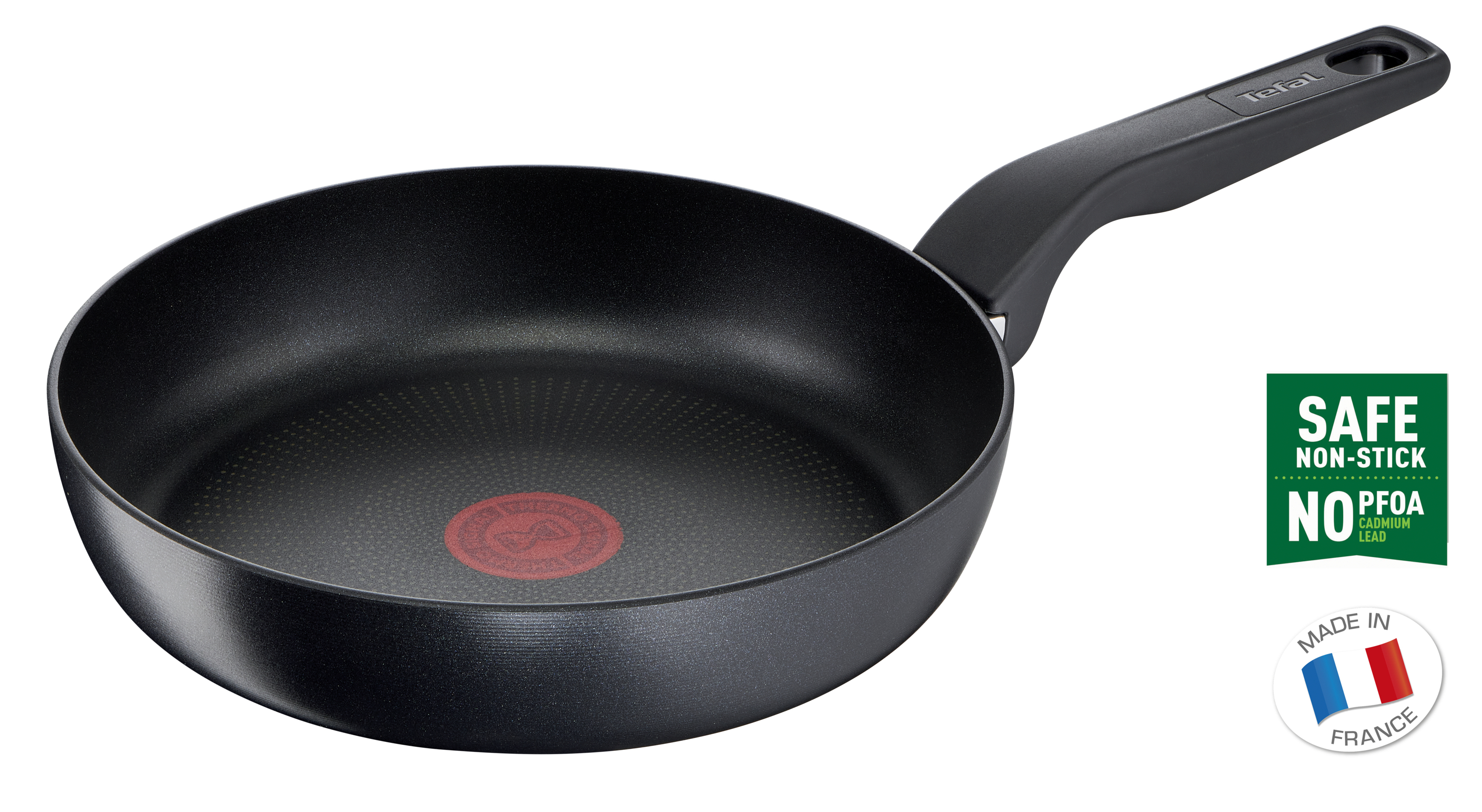 Czarna patelnia z długim uchwytem. Patelnia ma czerwoną kropkę pośrodku.