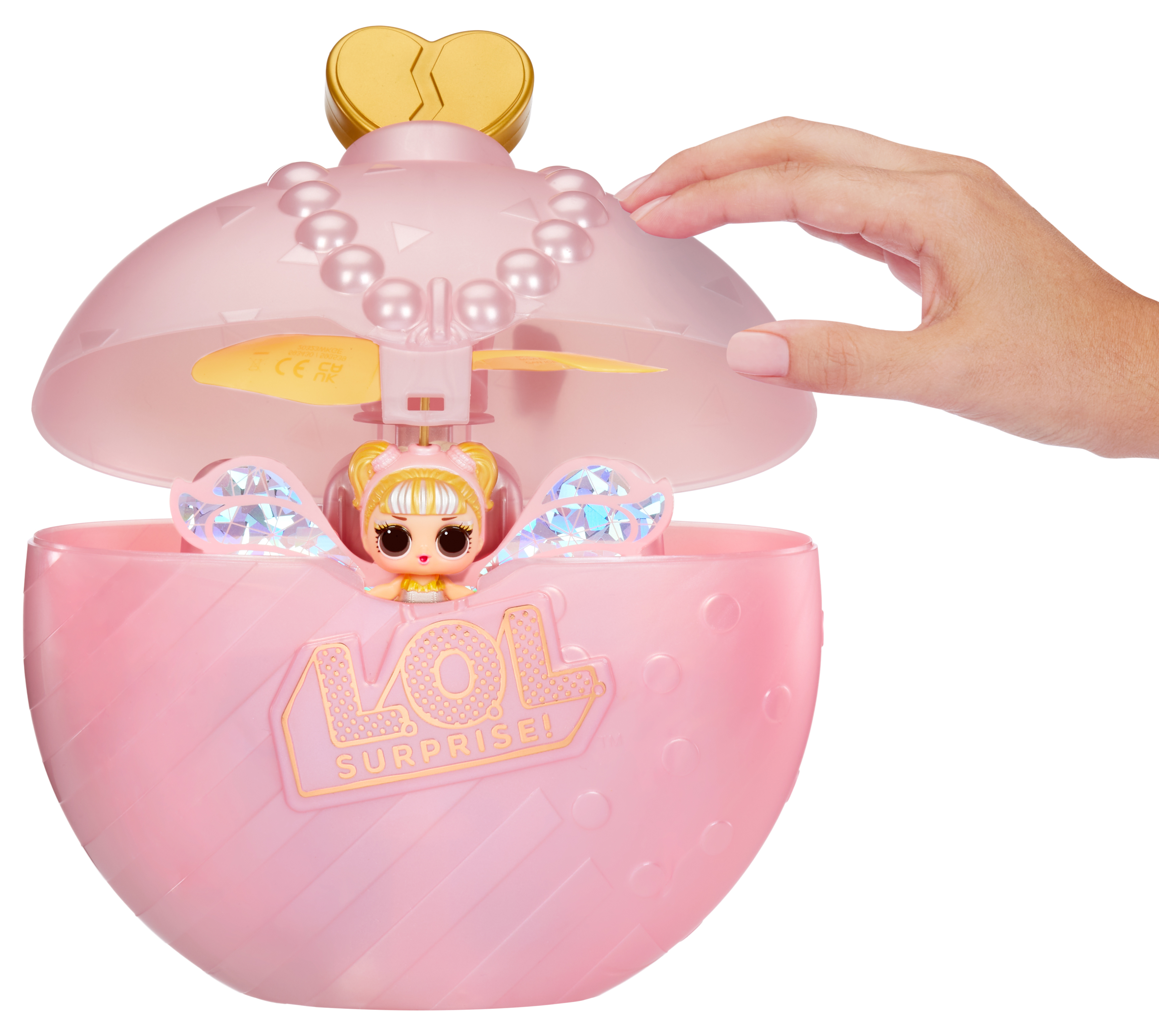 Różowa zabawka LOL Surprise z lalką w środku. Ręka otwiera zabawkę, ukazując lalkę i śmigło.