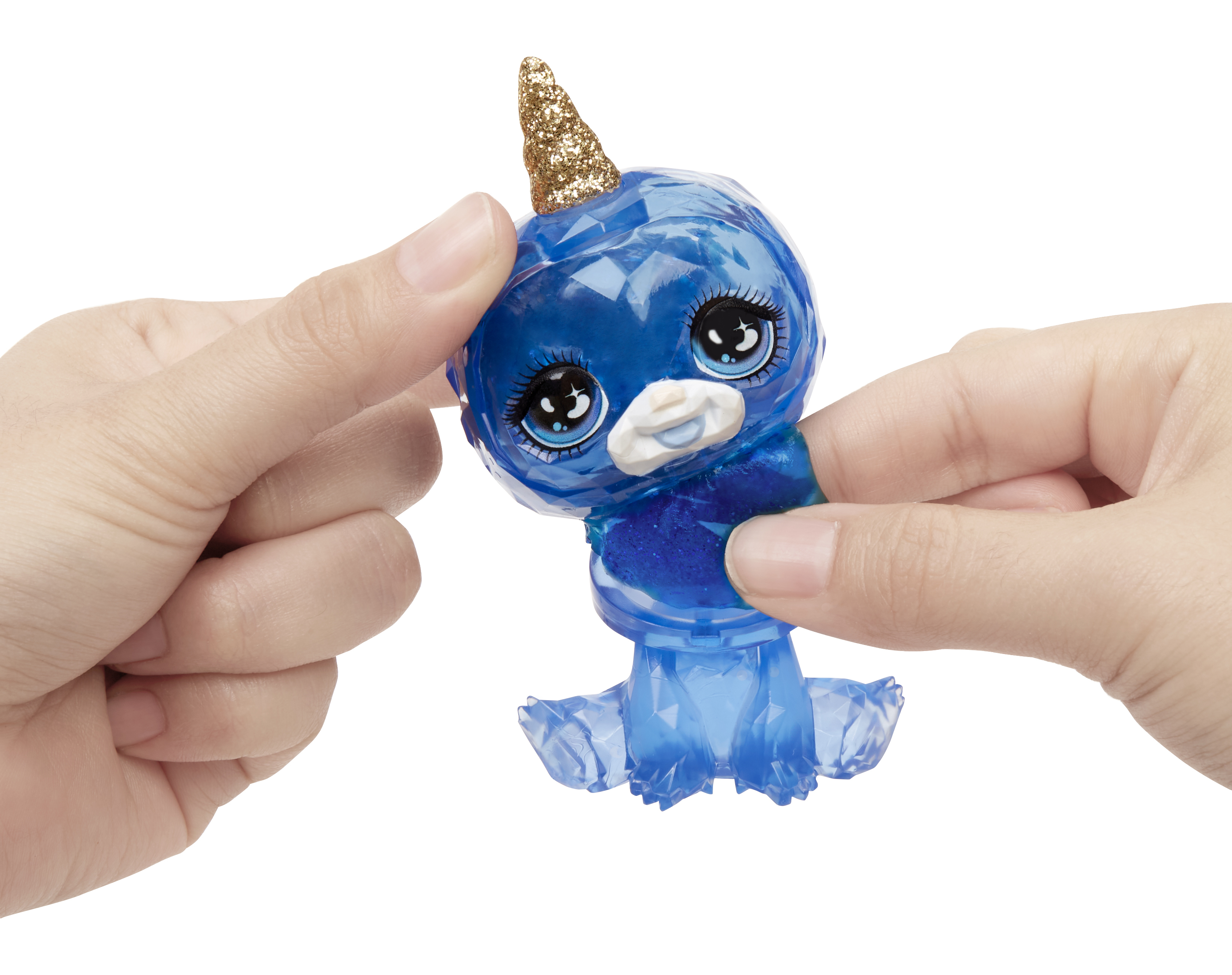 Niebieska, przypominająca klejnot zabawka w kształcie zwierzęcia ze złotym rogiem, trzymana w dłoniach.