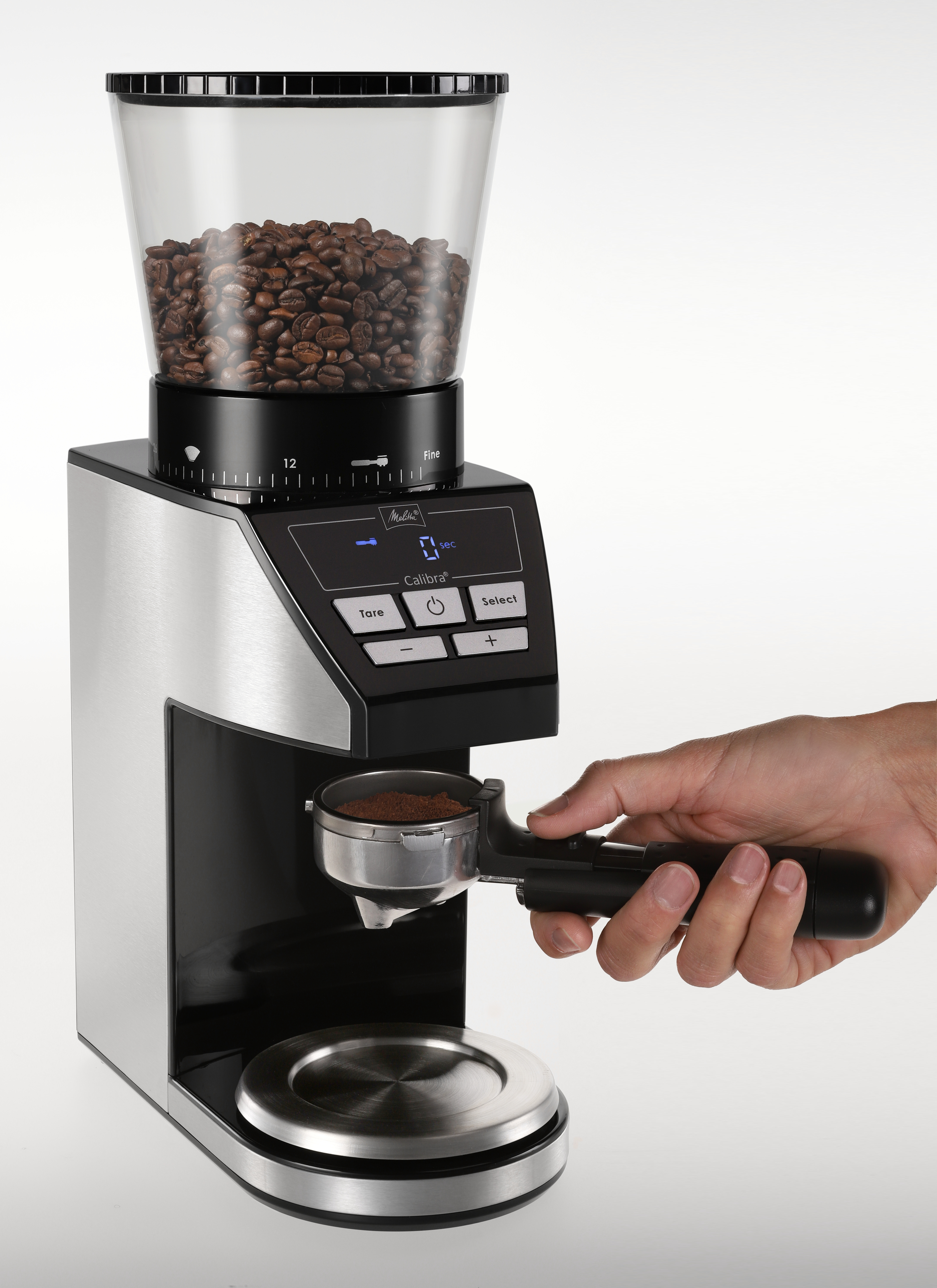 Kaffeemühle mit Bohnen und gemahlenem Kaffee. Person hält einen Siebträger. Digitalanzeige, Edelstahl.