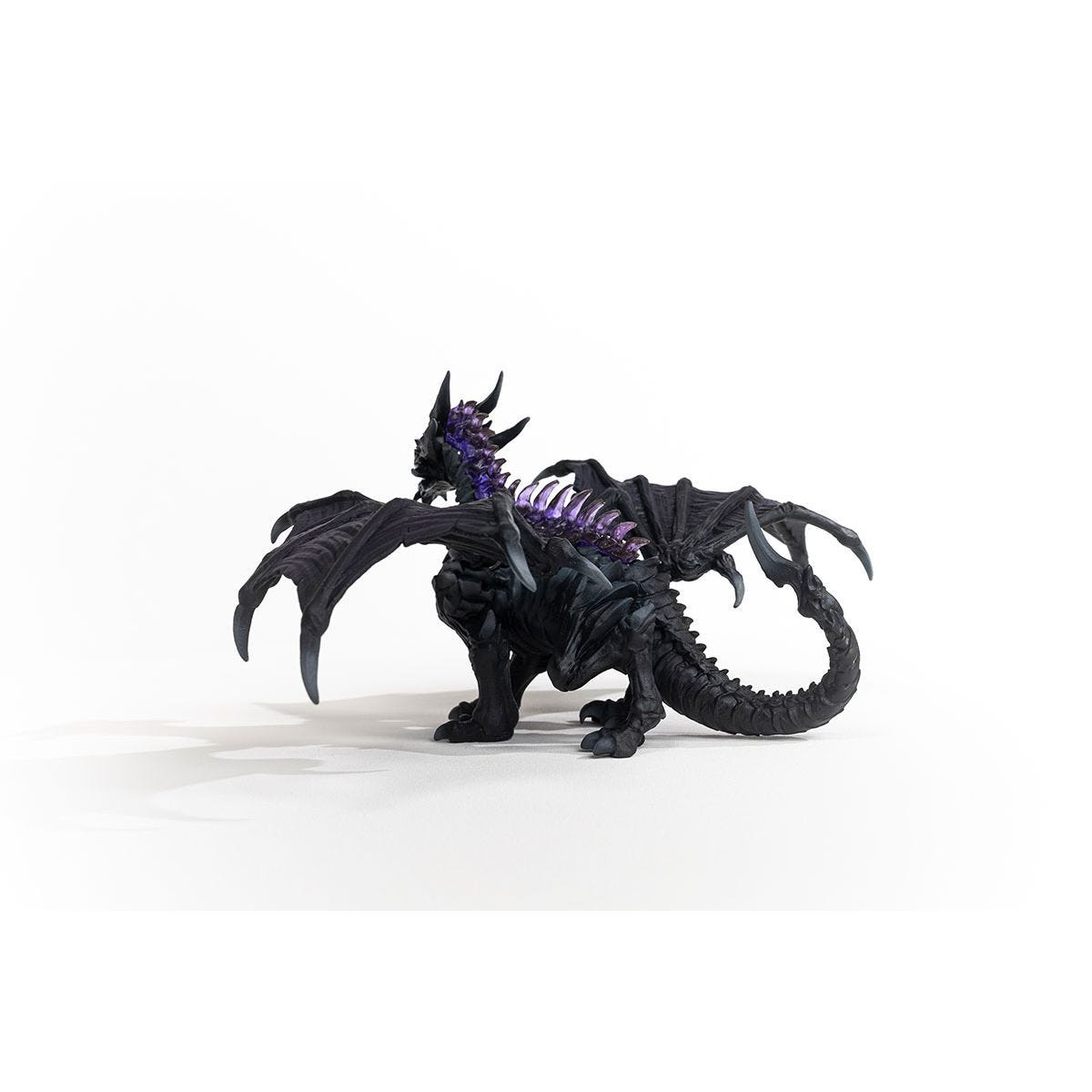 Un giocattolo di drago nero, con accenti e ali viola, su una superficie bianca.